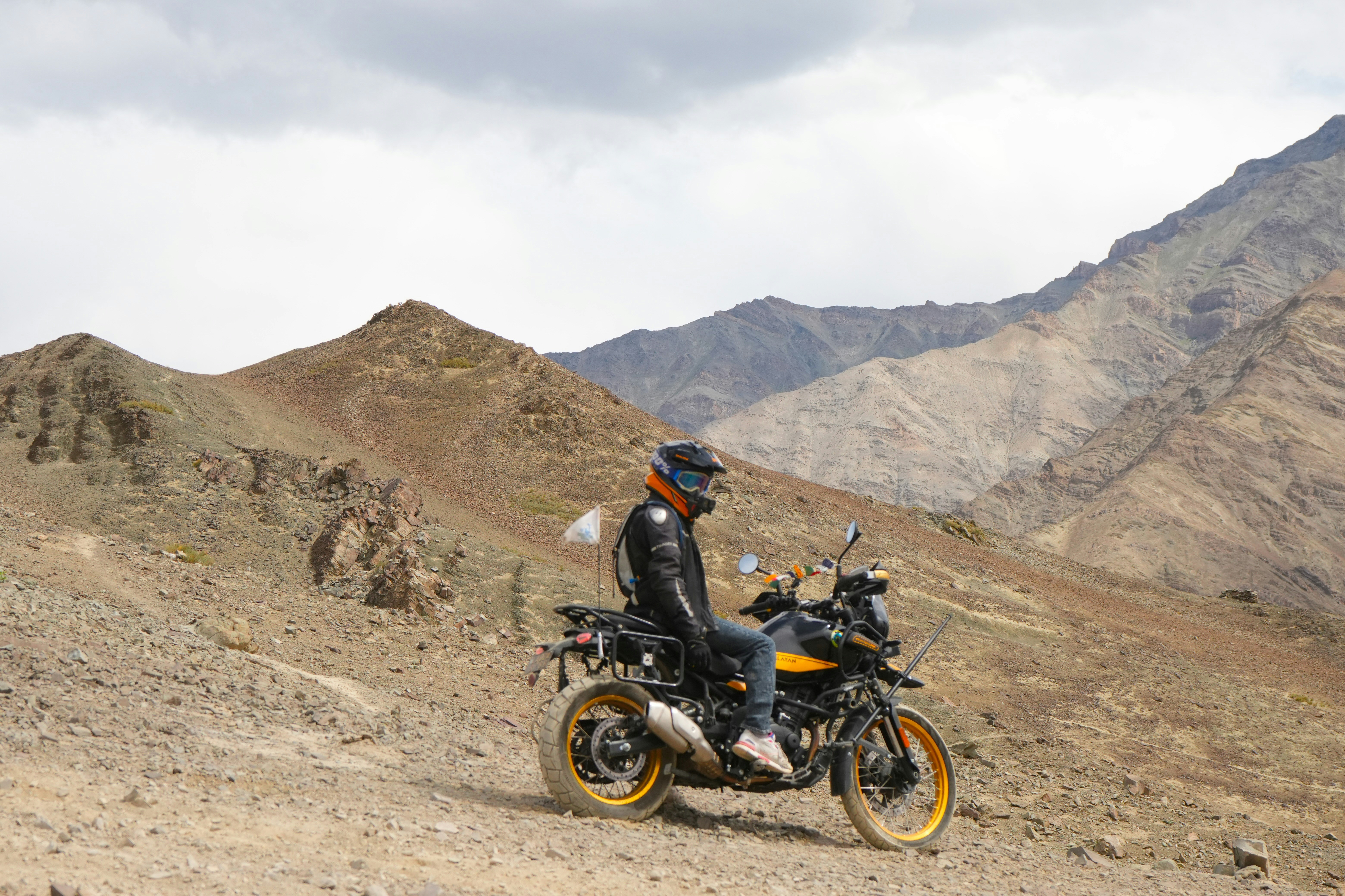 Person on motorcycle in a rocky, mountainous landscape.