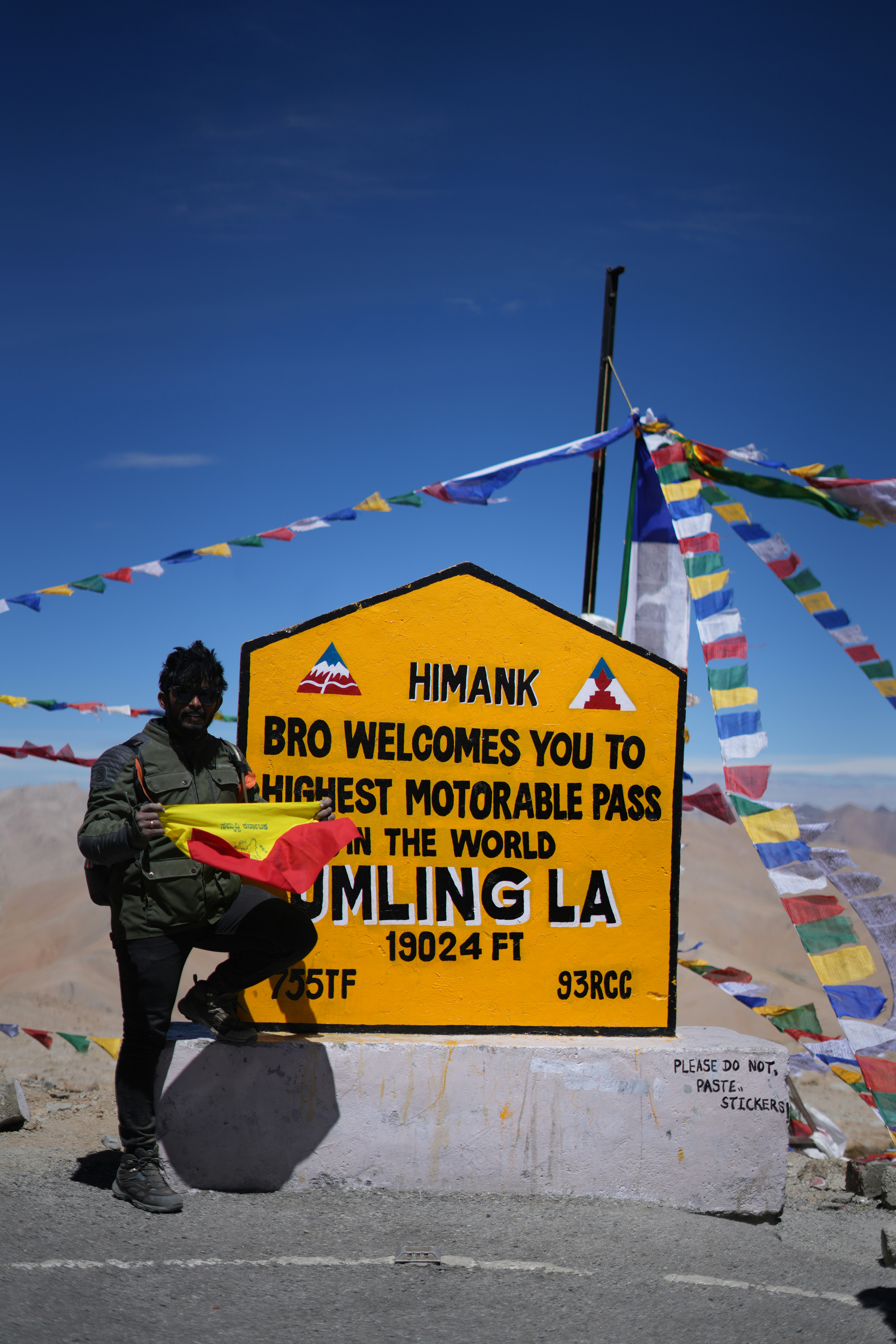 Man holding flag at highest motorable pass sign