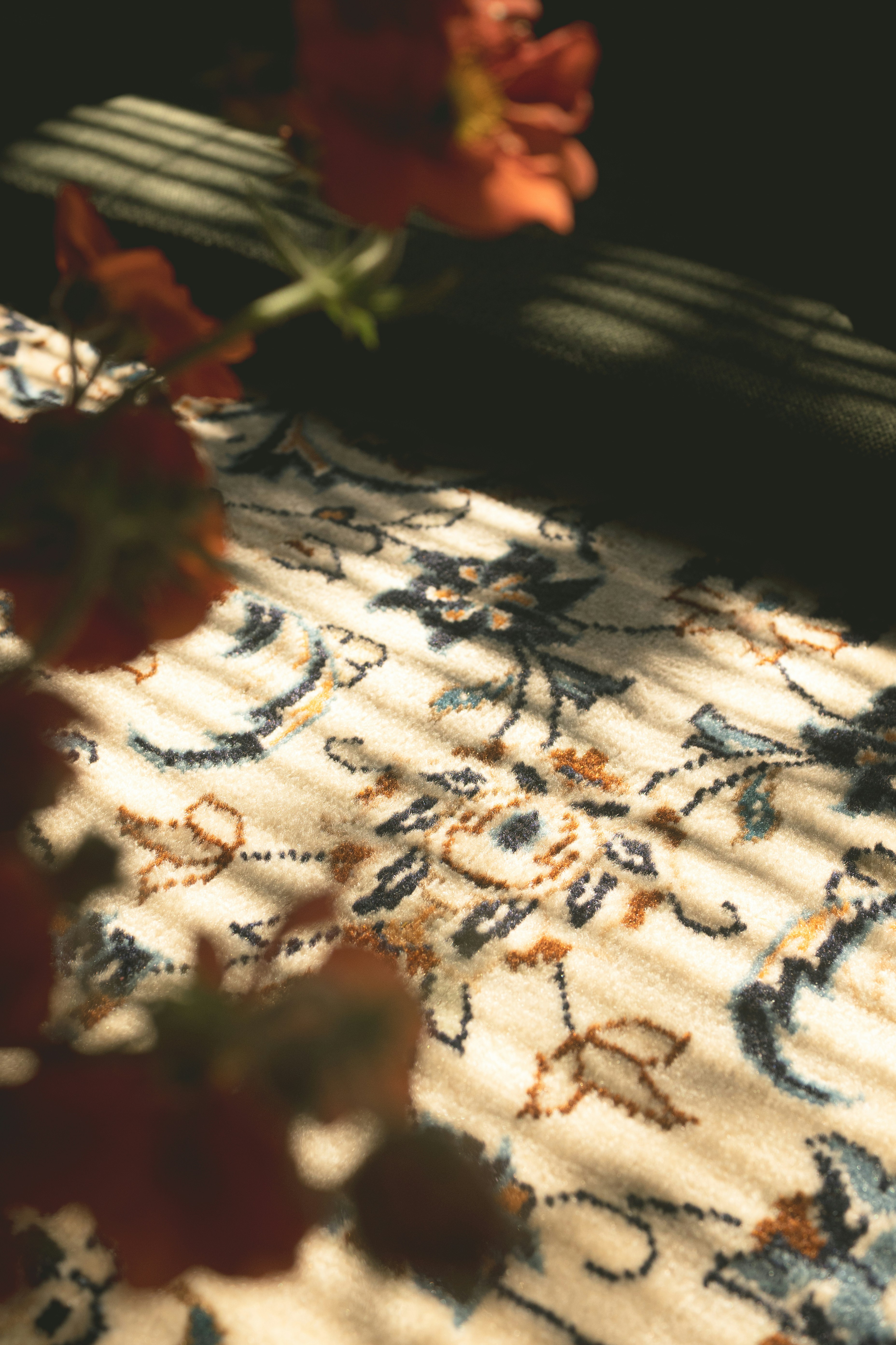 Close-up of a floral rug with striped light patterns.