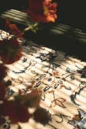 Close-up of a floral rug with striped light patterns.