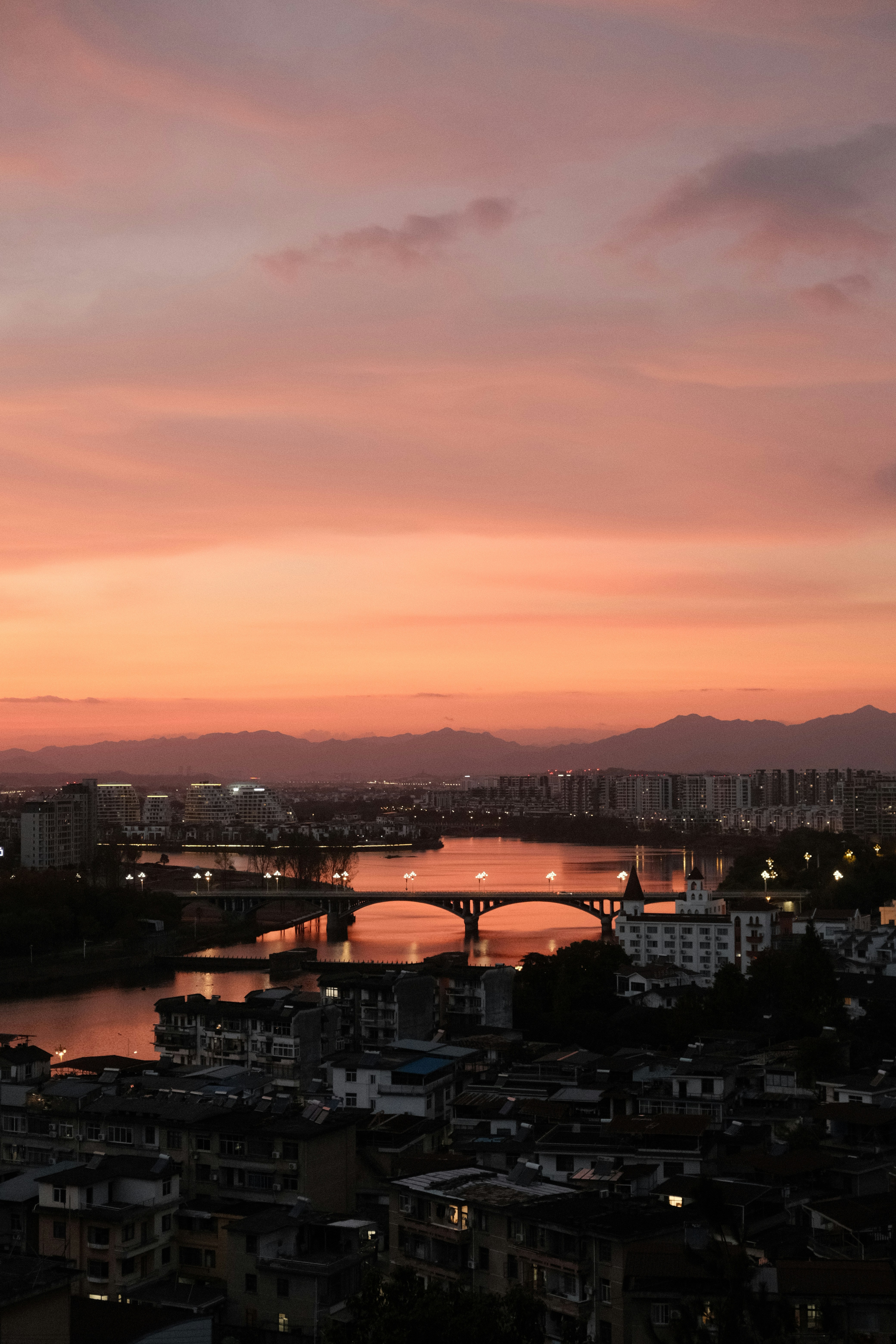 Cityscape with bridge over river at sunset