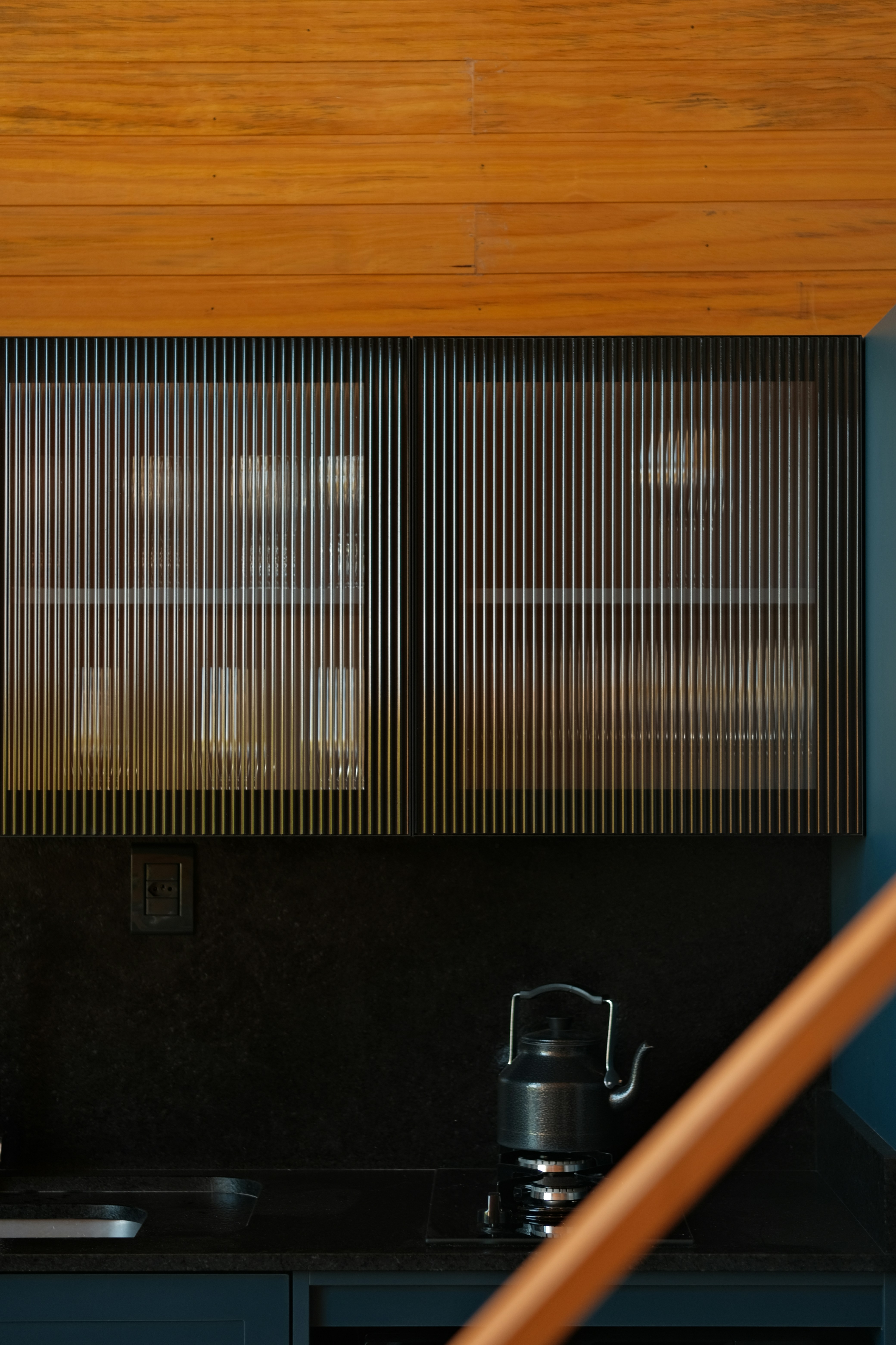 Modern kitchen with striped cabinet doors and kettle.