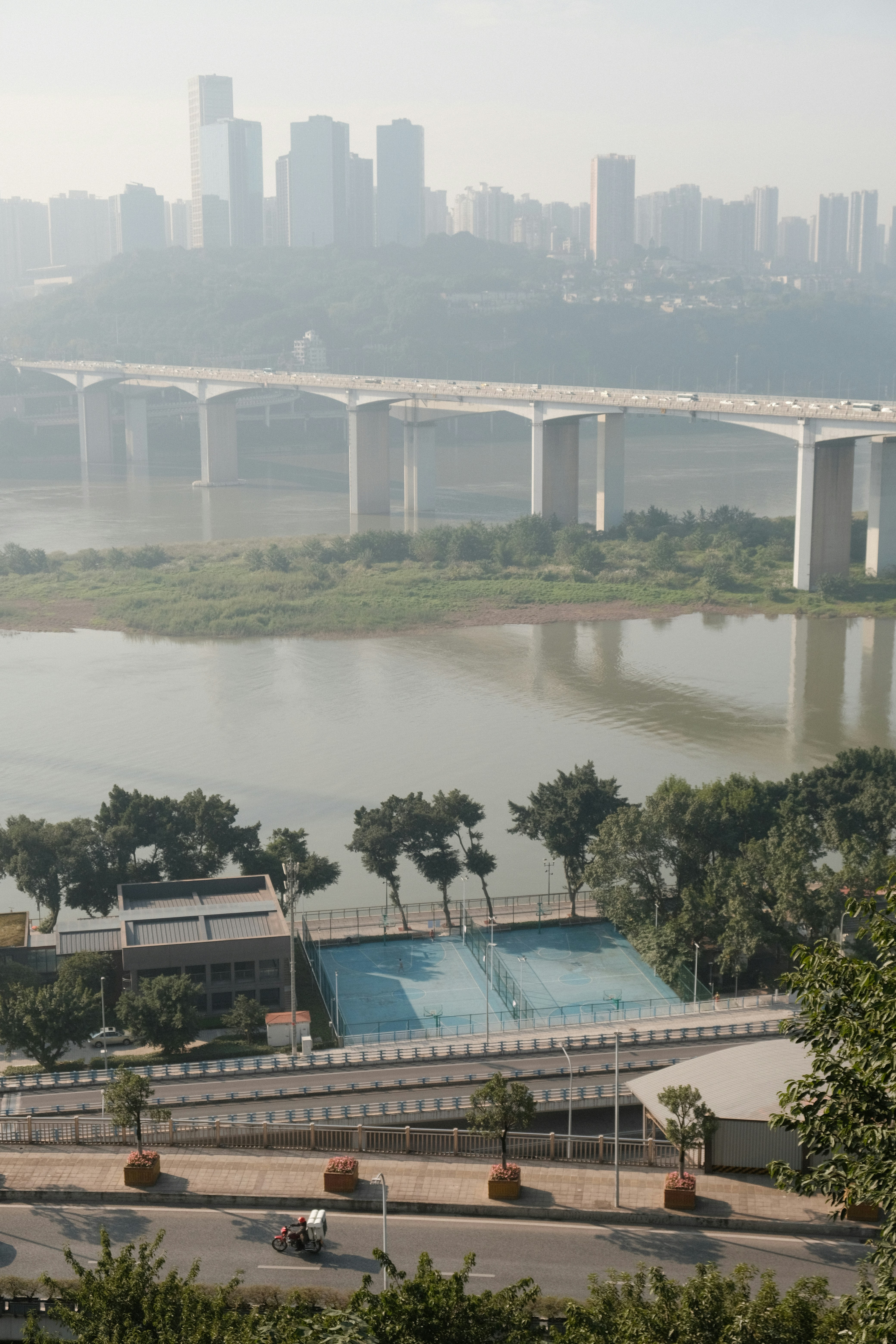 Modern bridge spans a wide river with city skyline