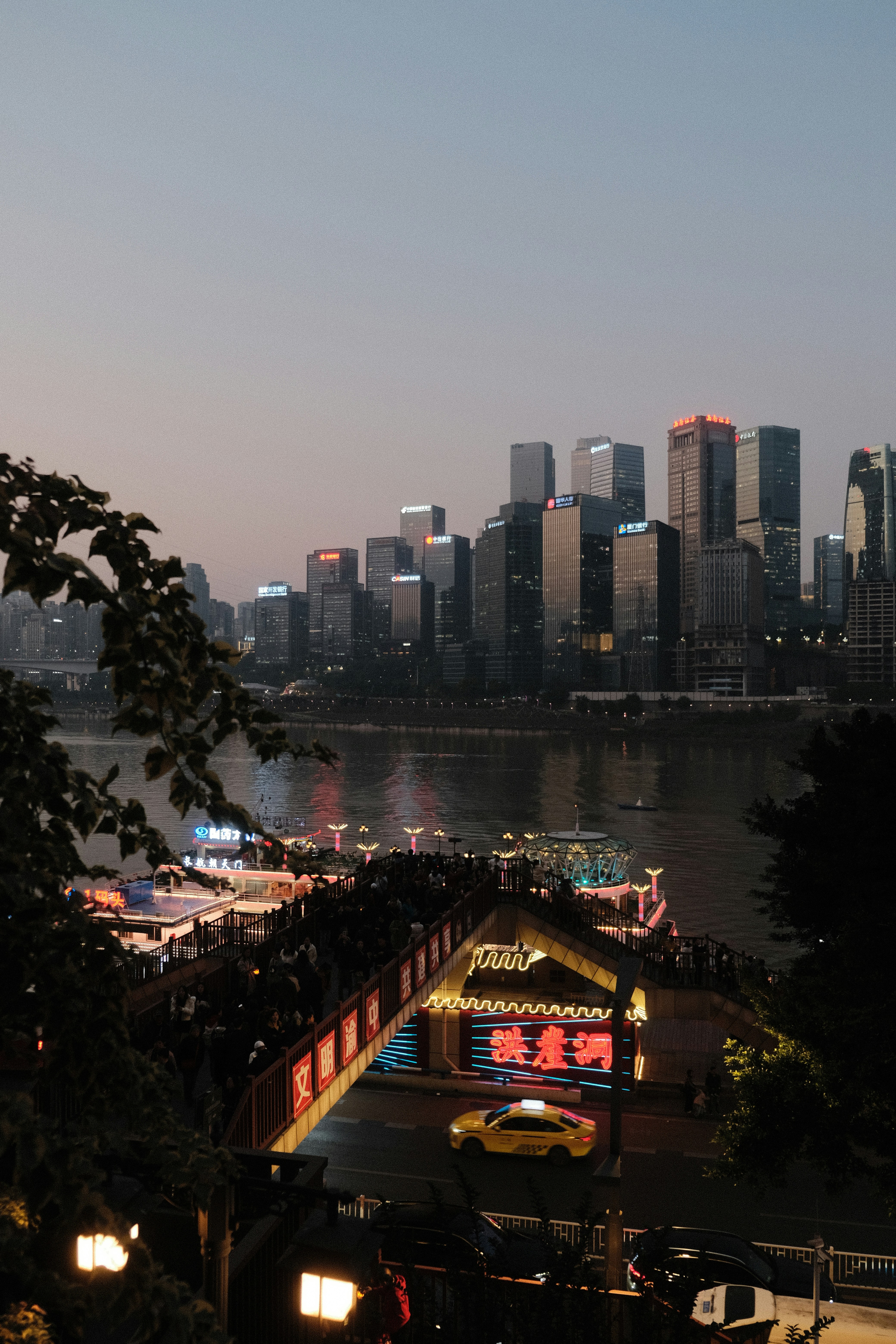 City skyline with a river and illuminated bridge at dusk