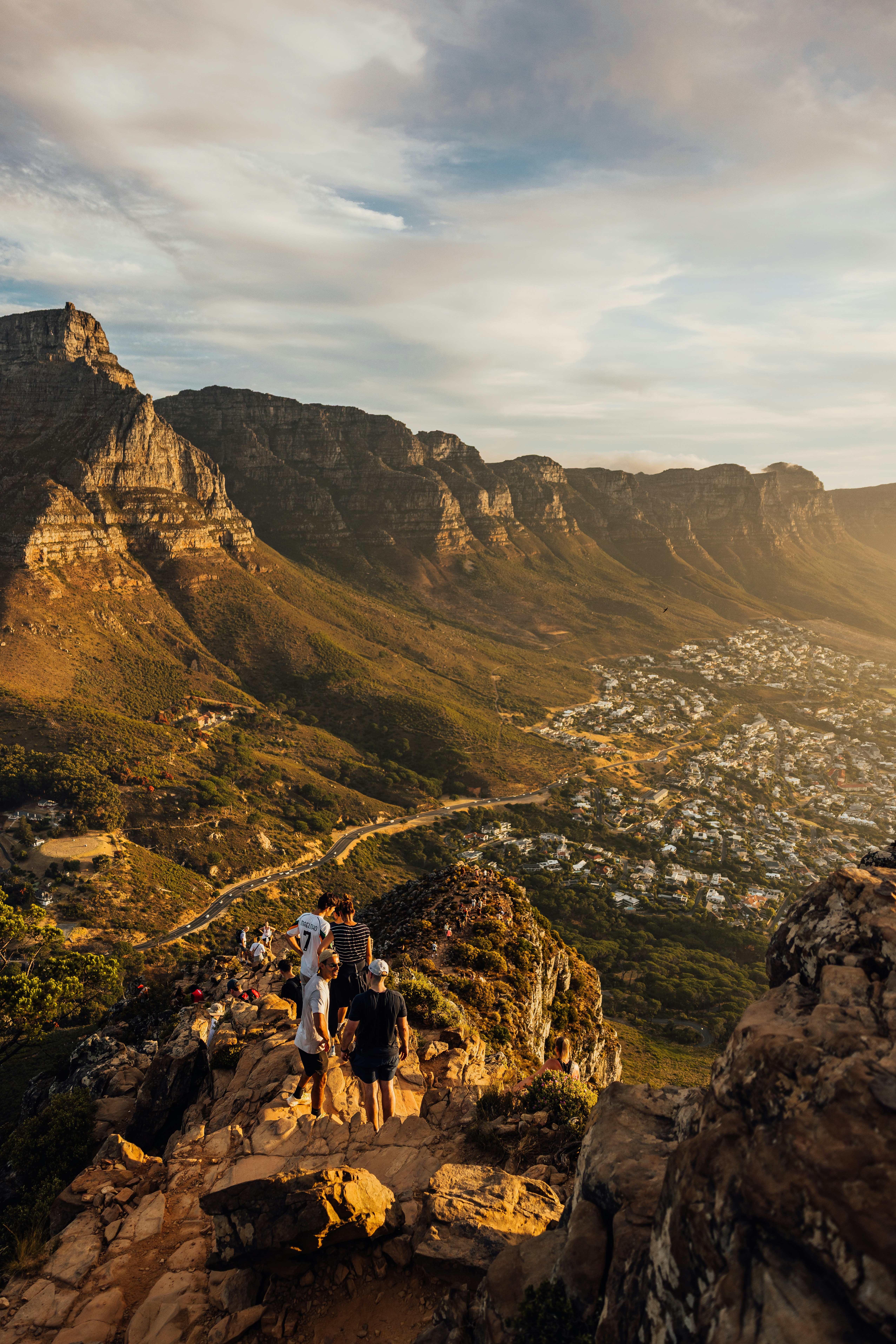 People admire a sunlit mountain range overlooking a town.