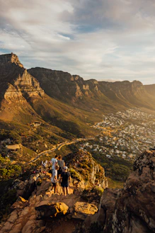 People admire a sunlit mountain range overlooking a town.