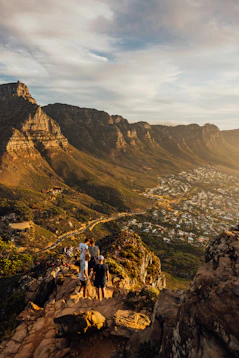 People admire a sunlit mountain range overlooking a town.