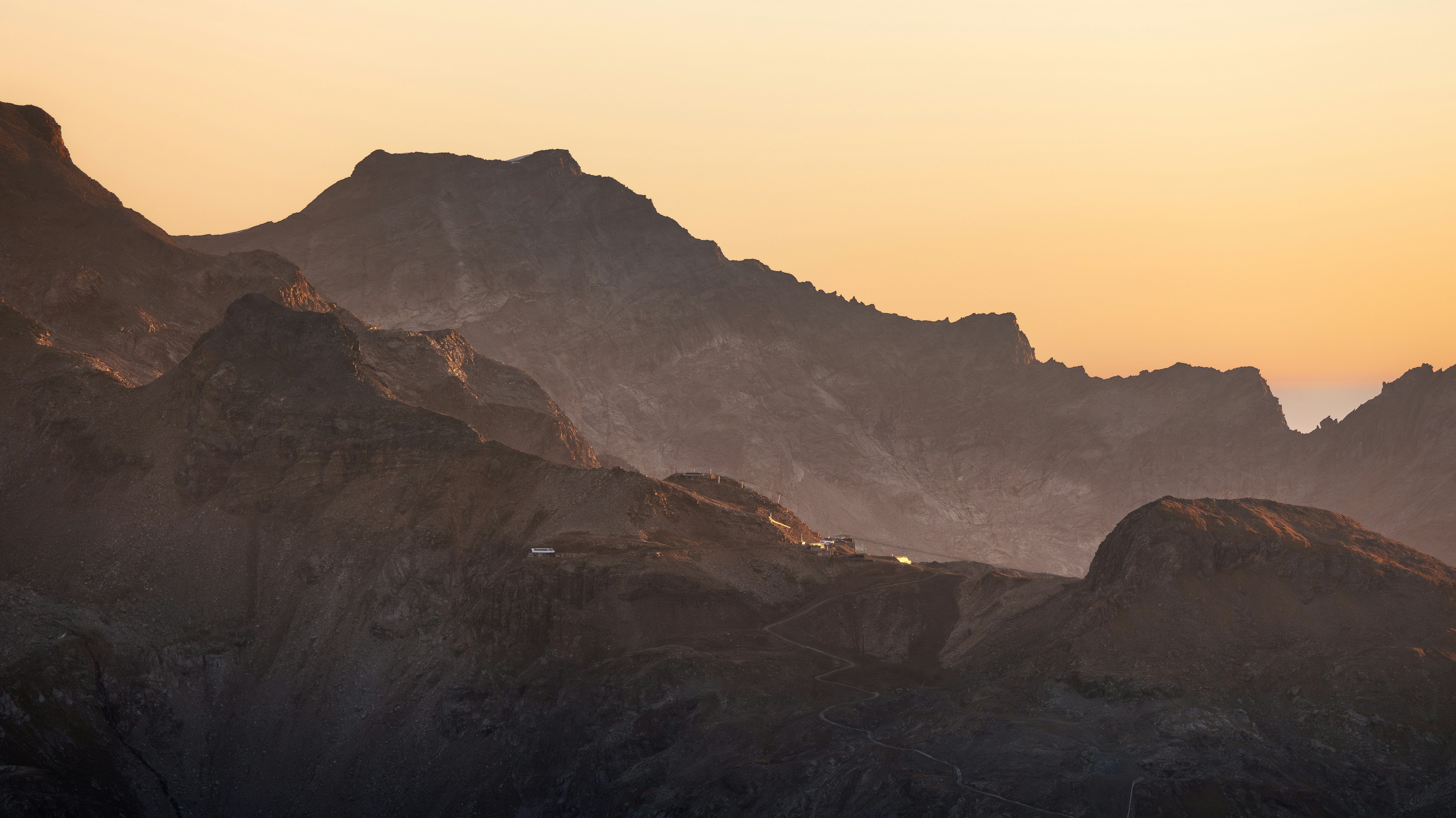 Mountain range silhouette against a soft orange sky