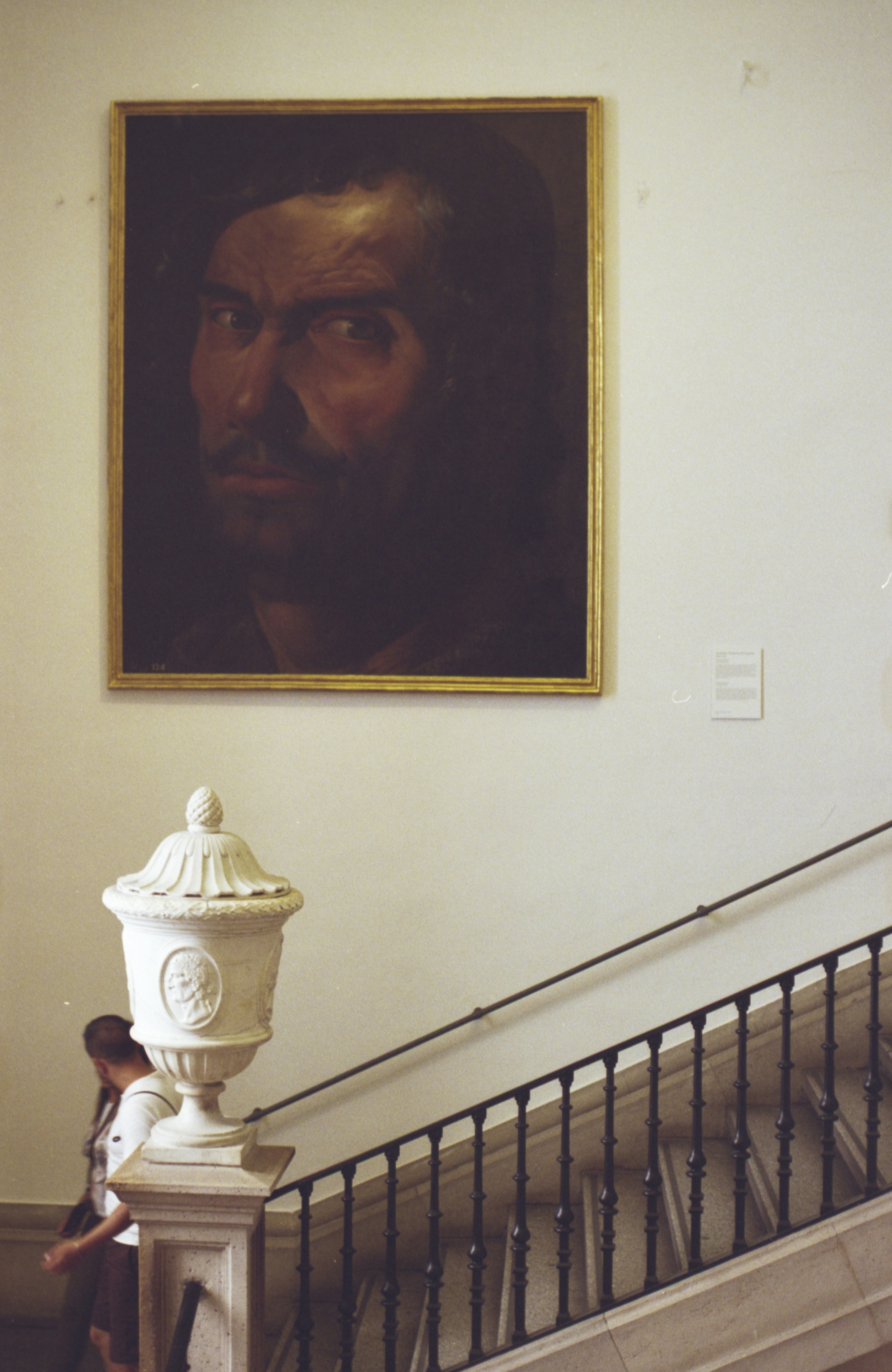 Painting of a man's face above a staircase railing.