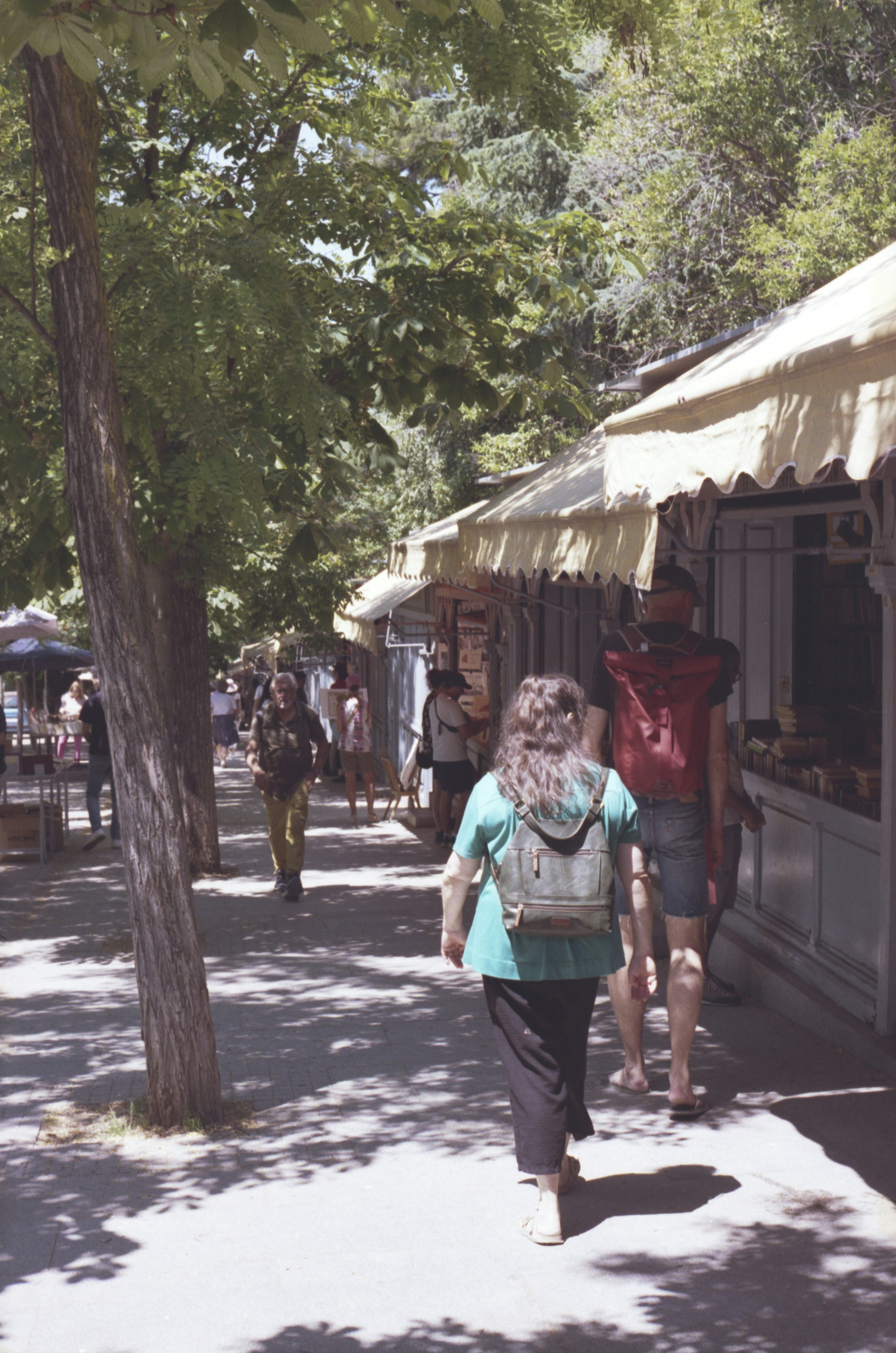 People walking down a sunny market street.
