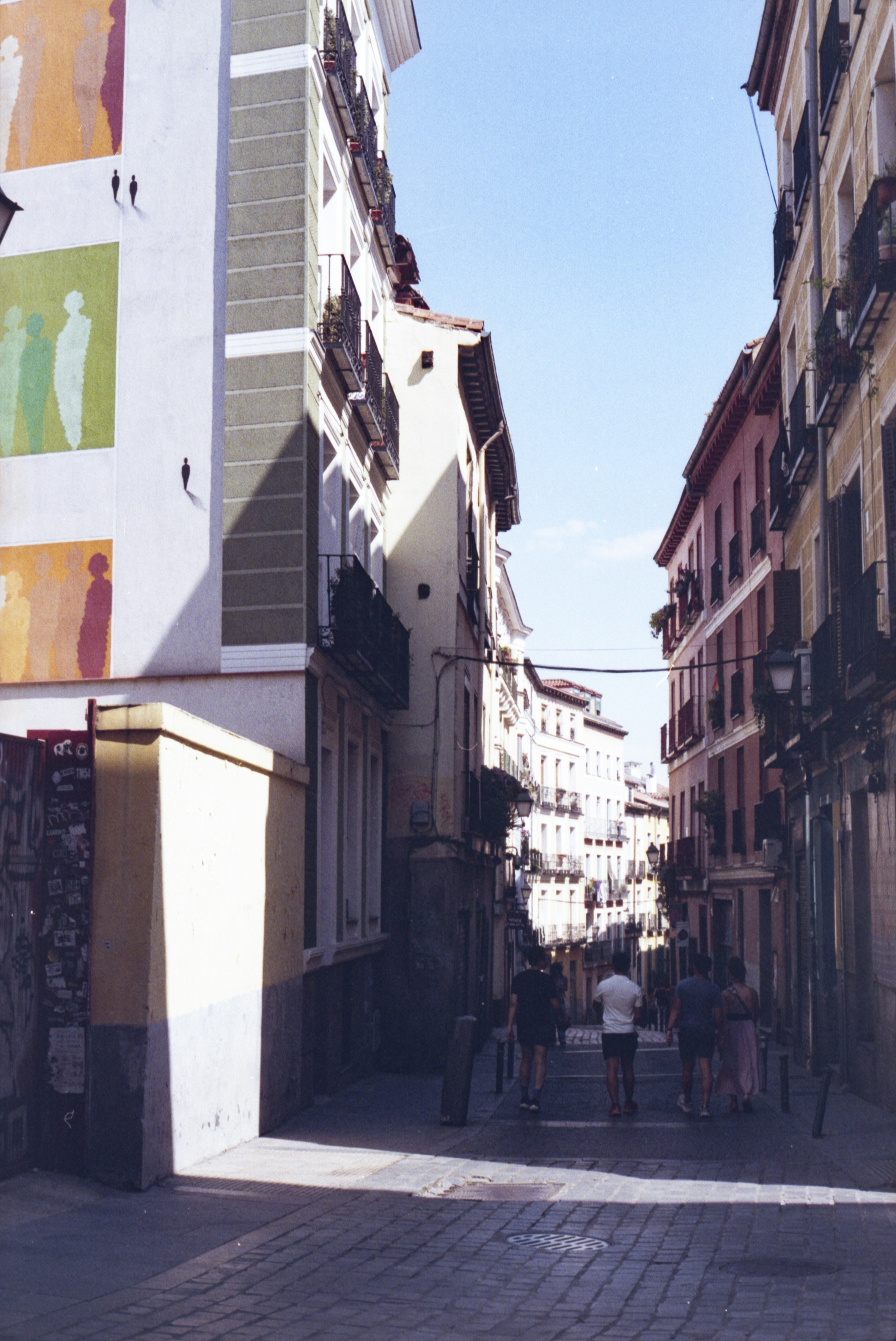 People walk down a narrow street lined with buildings.