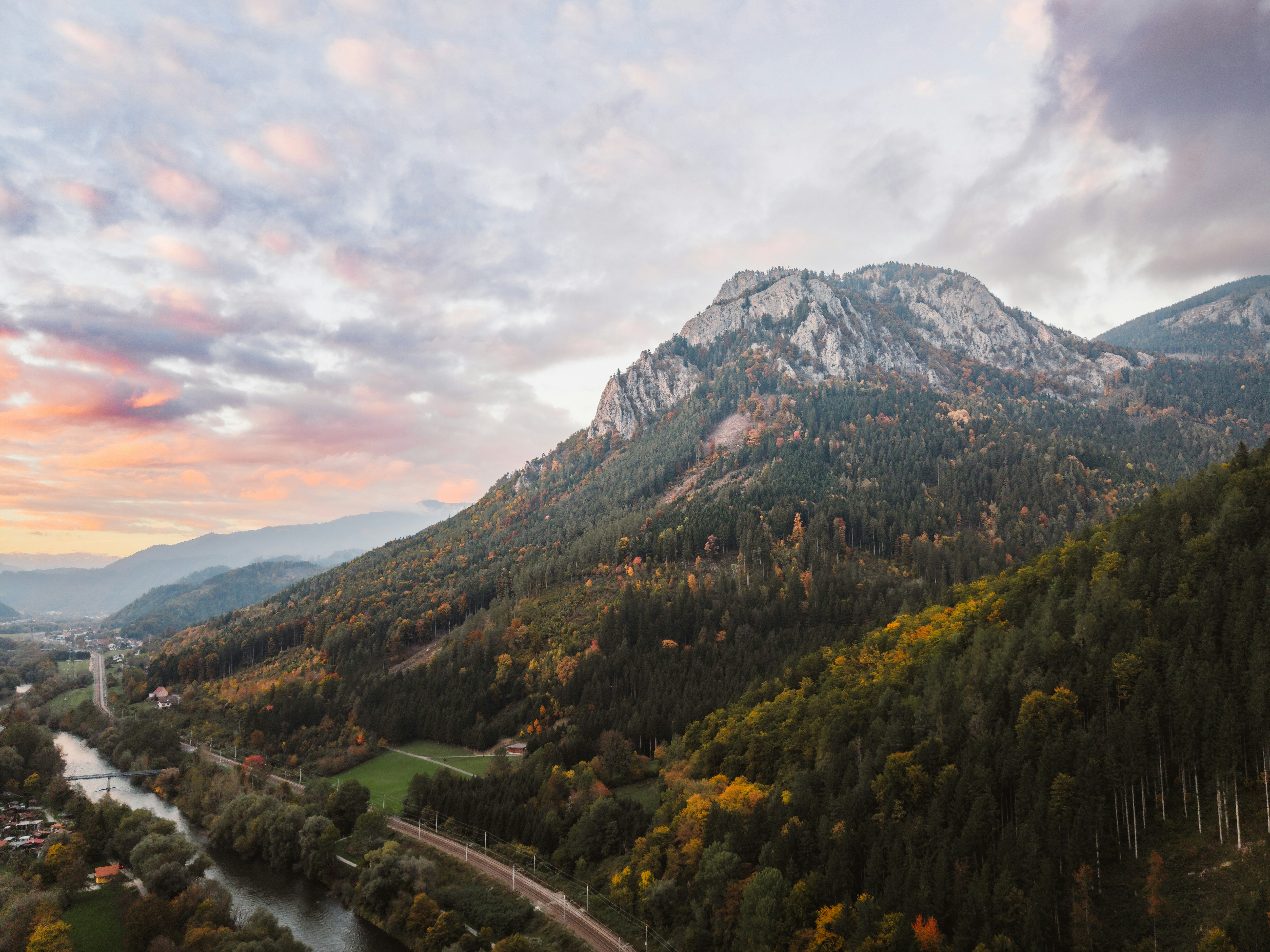 Majestic mountain range with a river and autumn forest.
