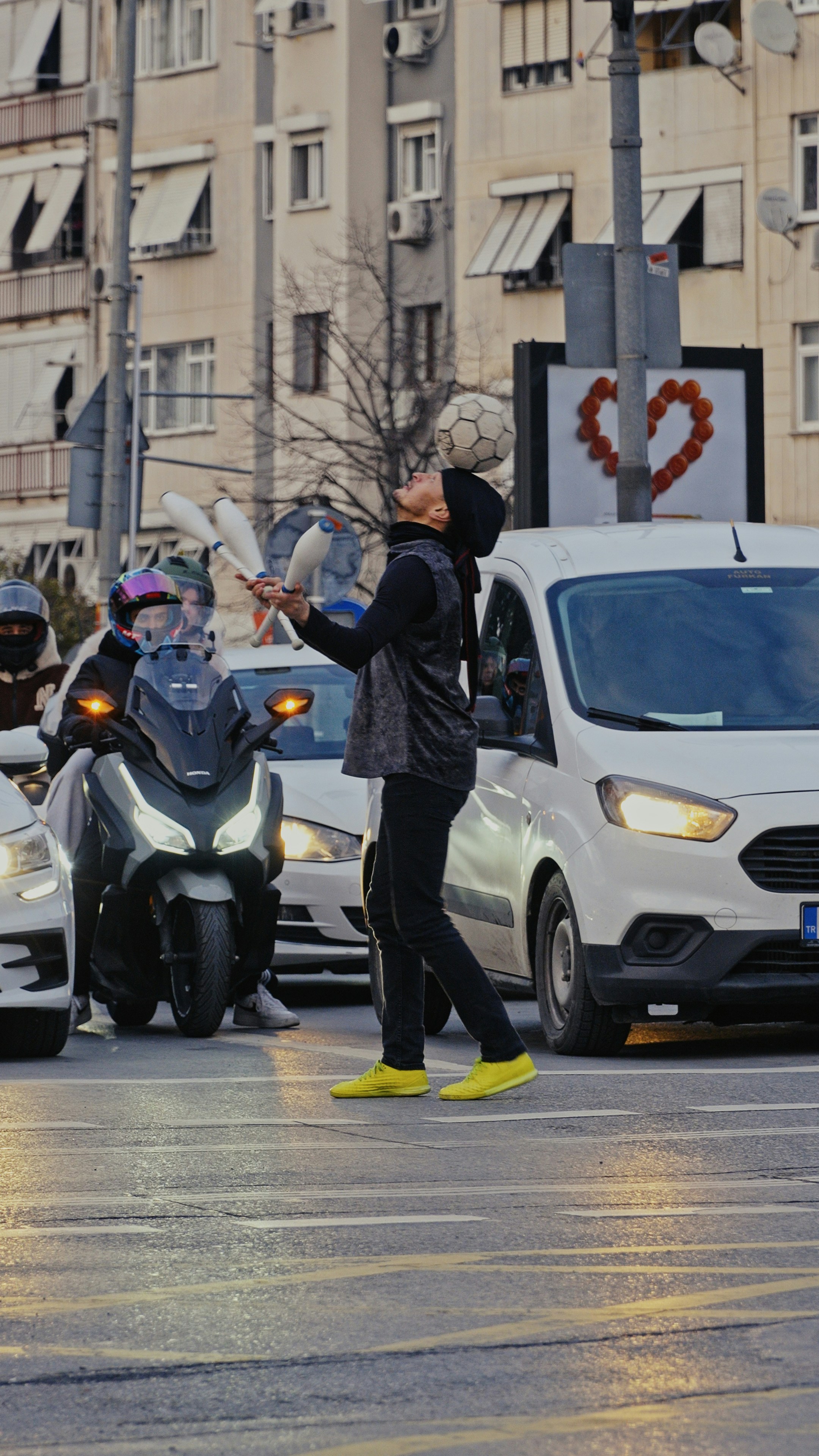 A street performer juggles a soccer ball and pins.