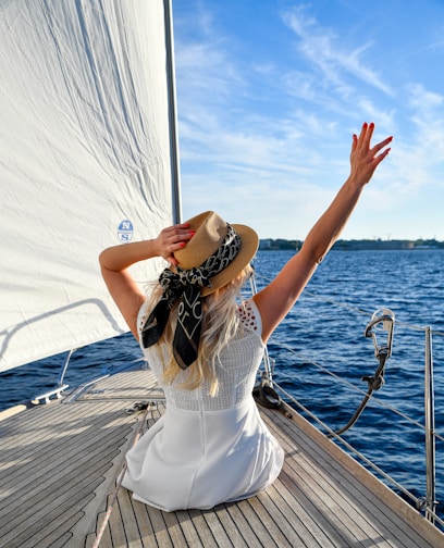 Woman in white dress on sailboat with arms raised