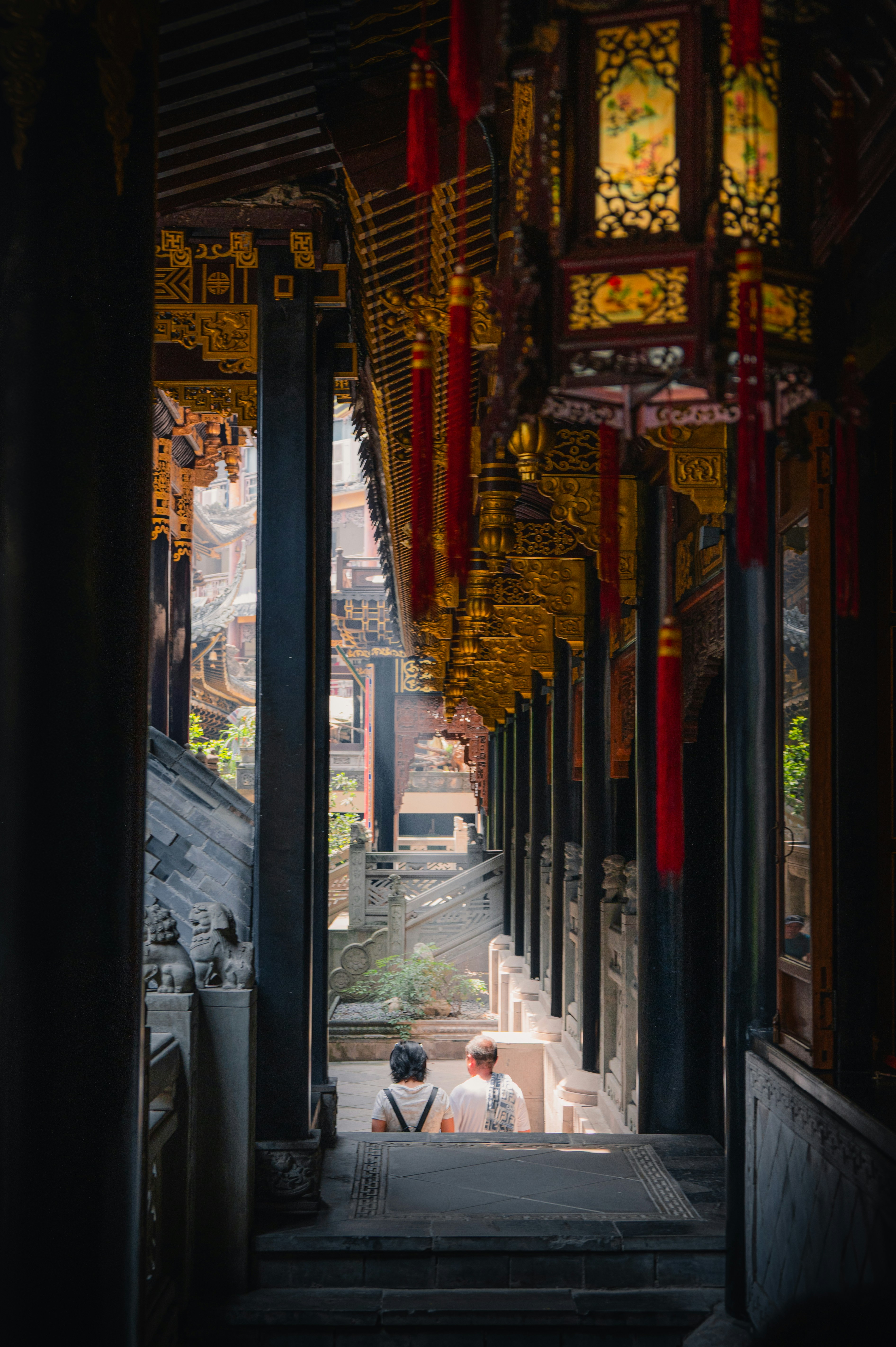 Two people walk down steps under ornate lanterns
