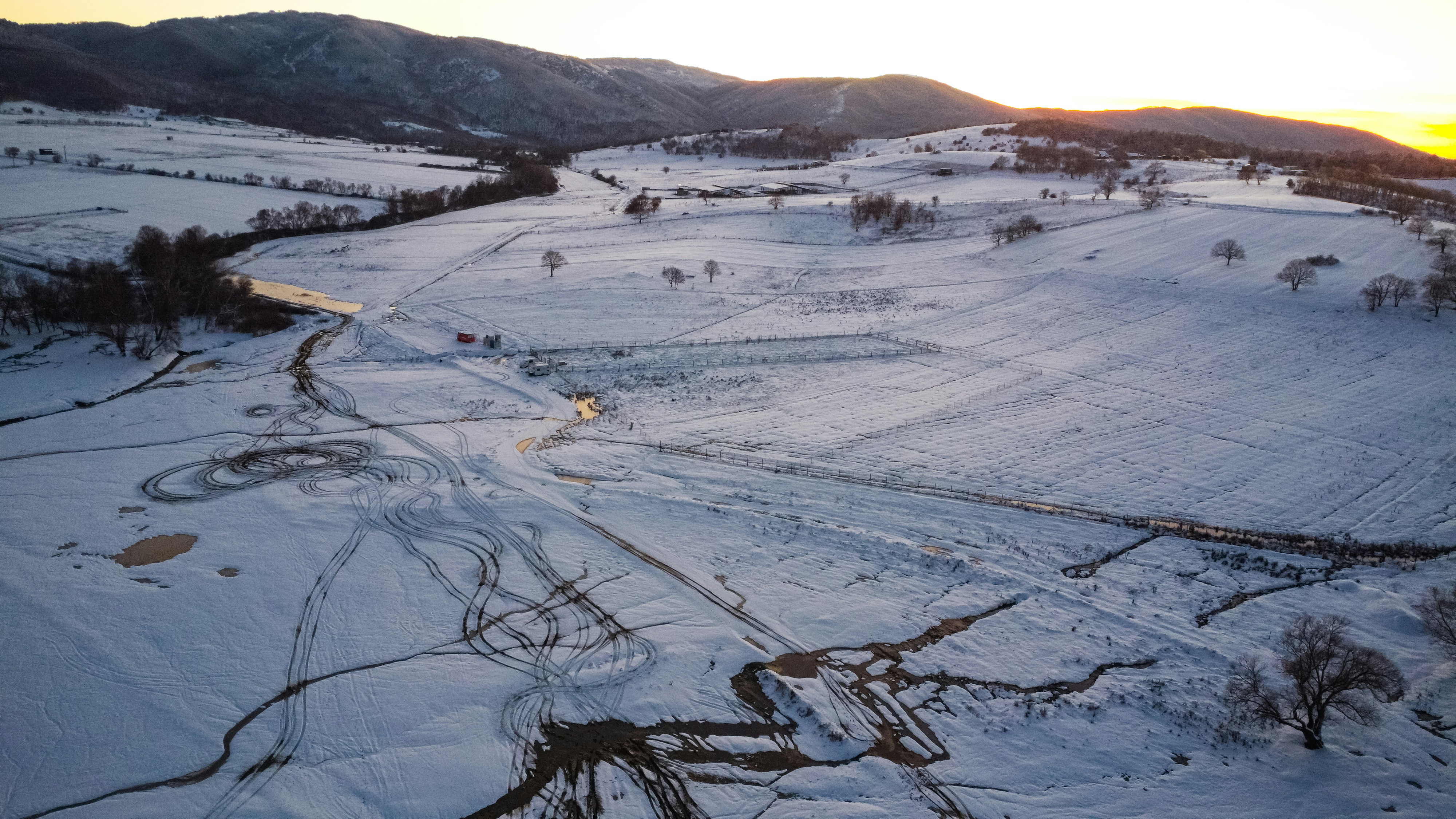 Snowy landscape with rolling hills at sunset