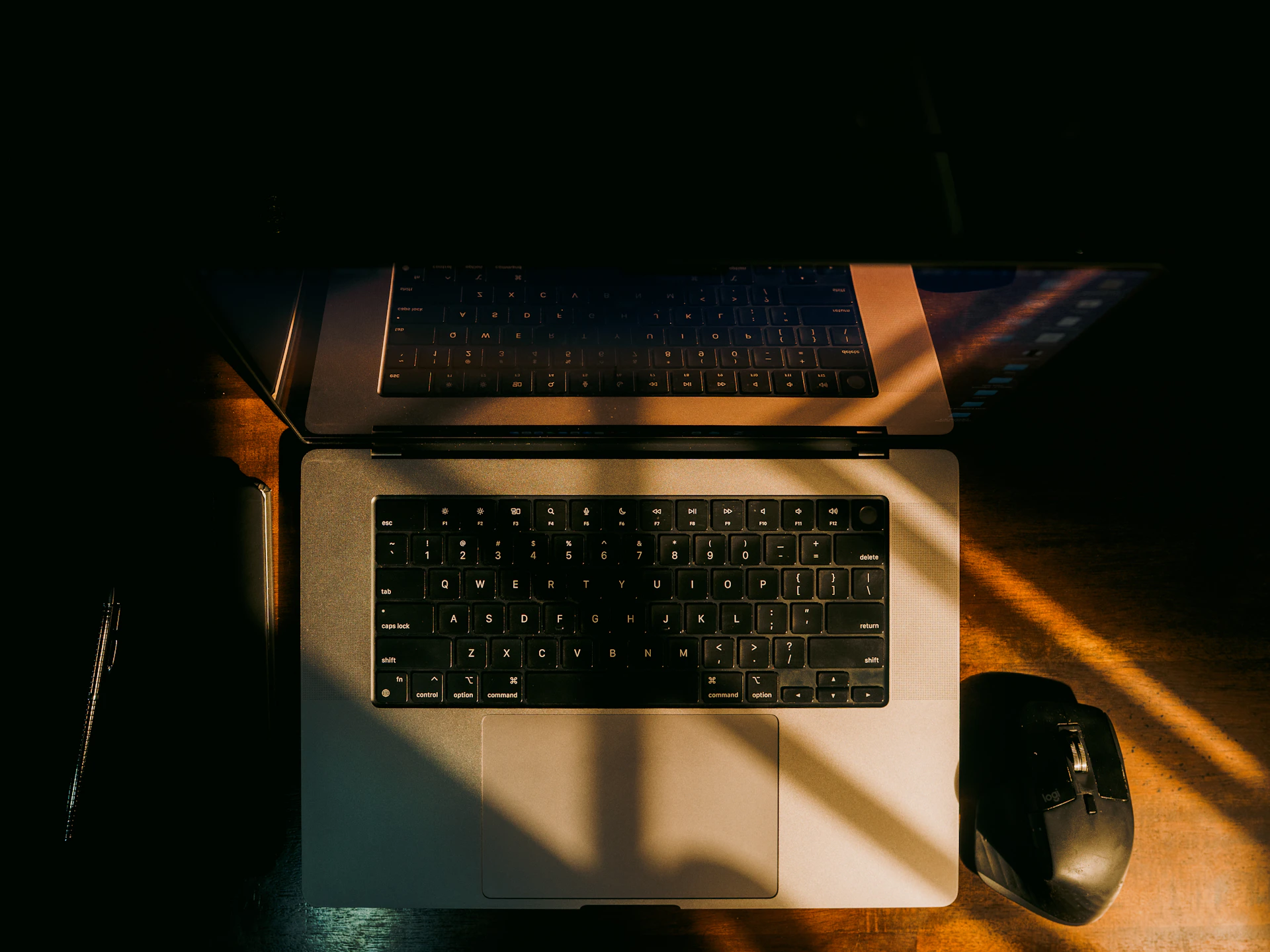 Laptop, mouse, and pen illuminated by sunlight