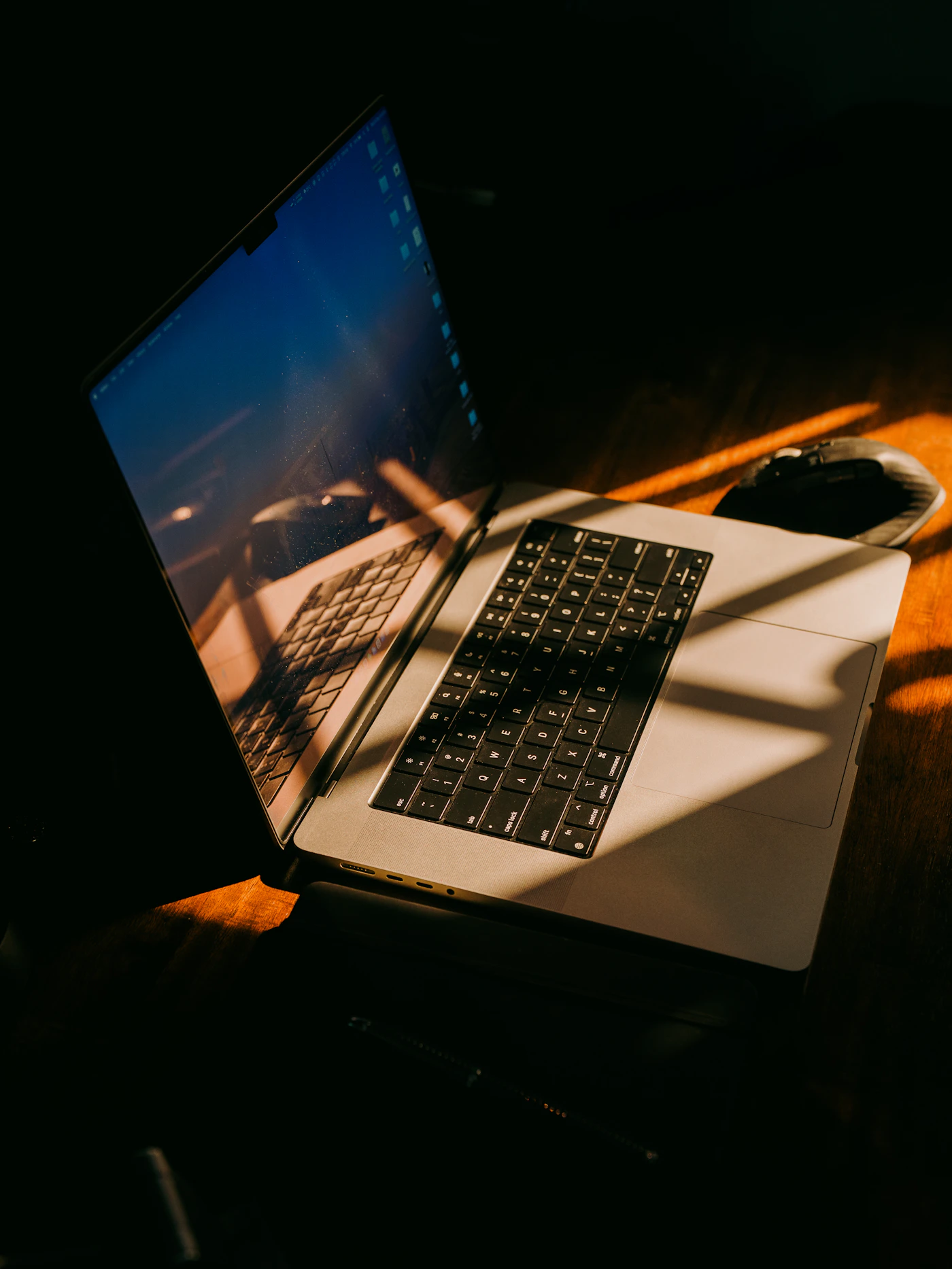 Laptop and mouse on a desk in warm natural light