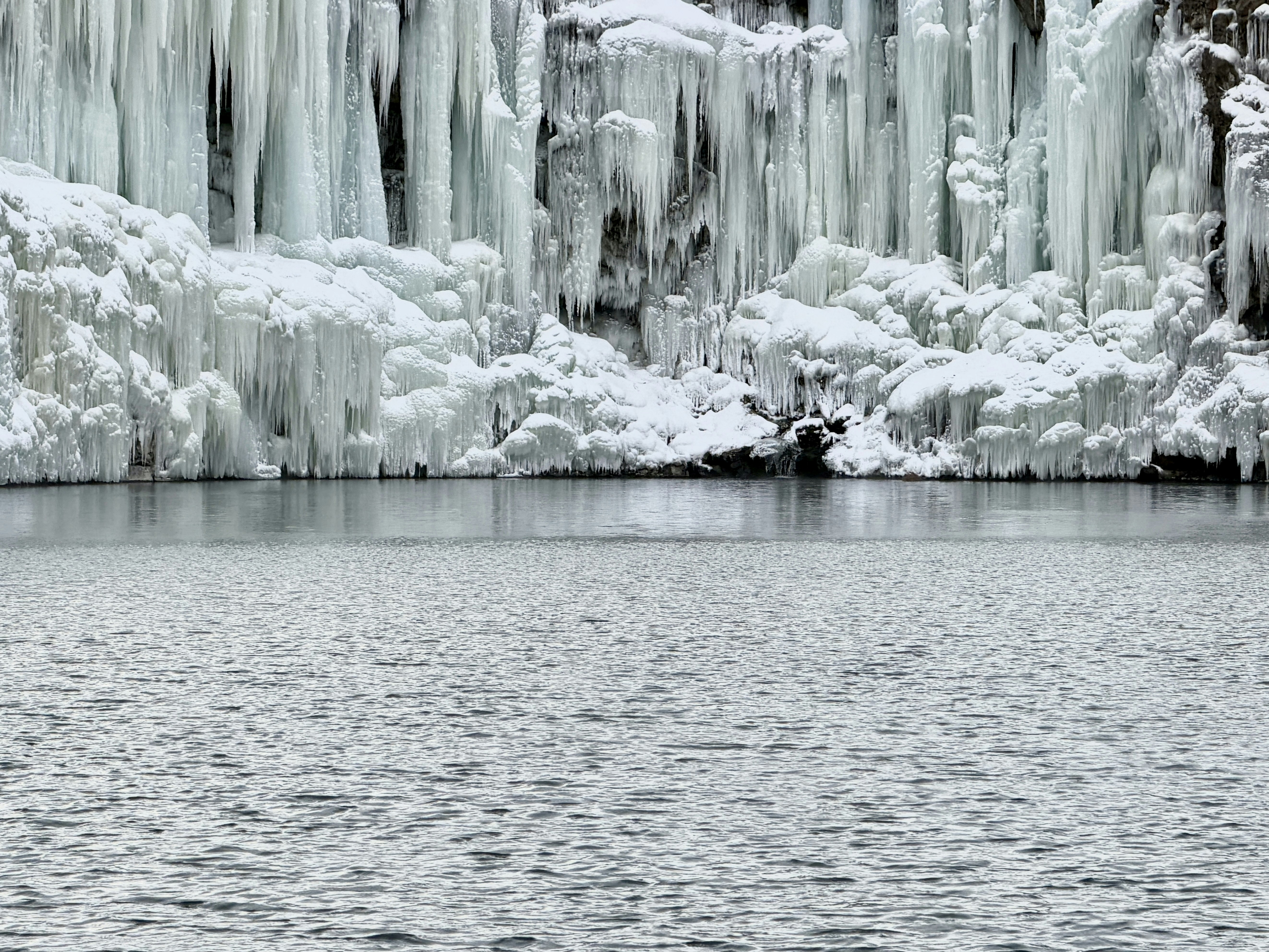 Frozen waterfall with icy formations above water