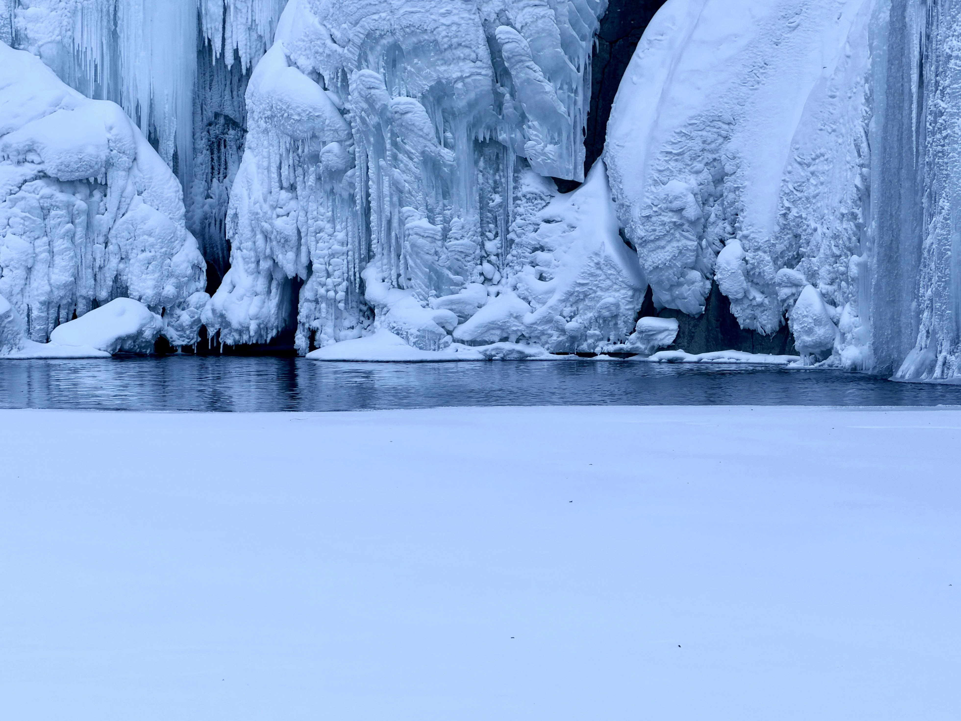 Frozen waterfall with icy formations and calm water
