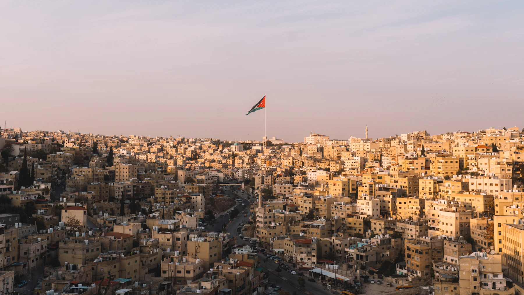 Amman cityscape and the Jordanian flag at sunset