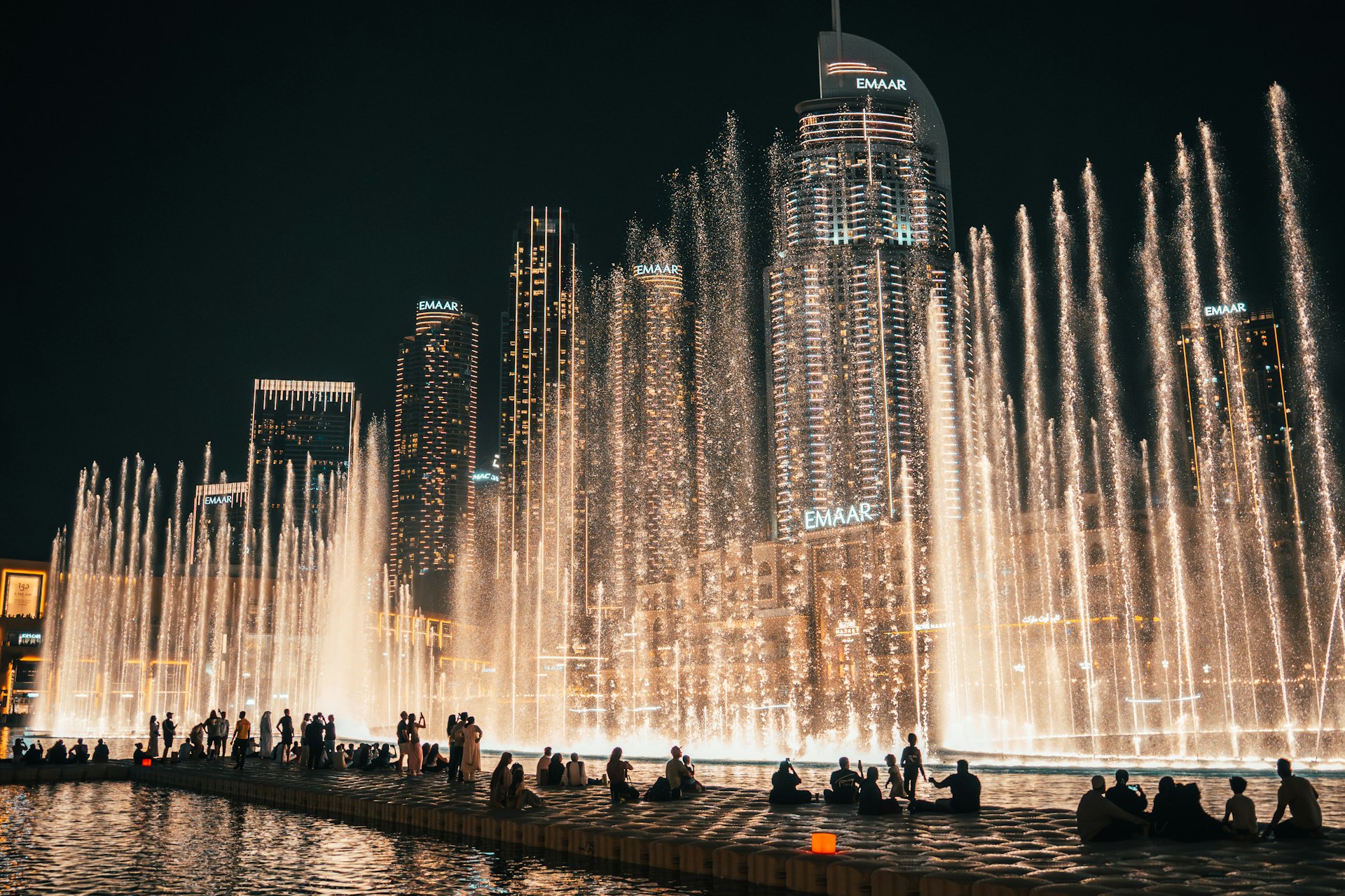 Spectacular water fountain show at night with city skyline.