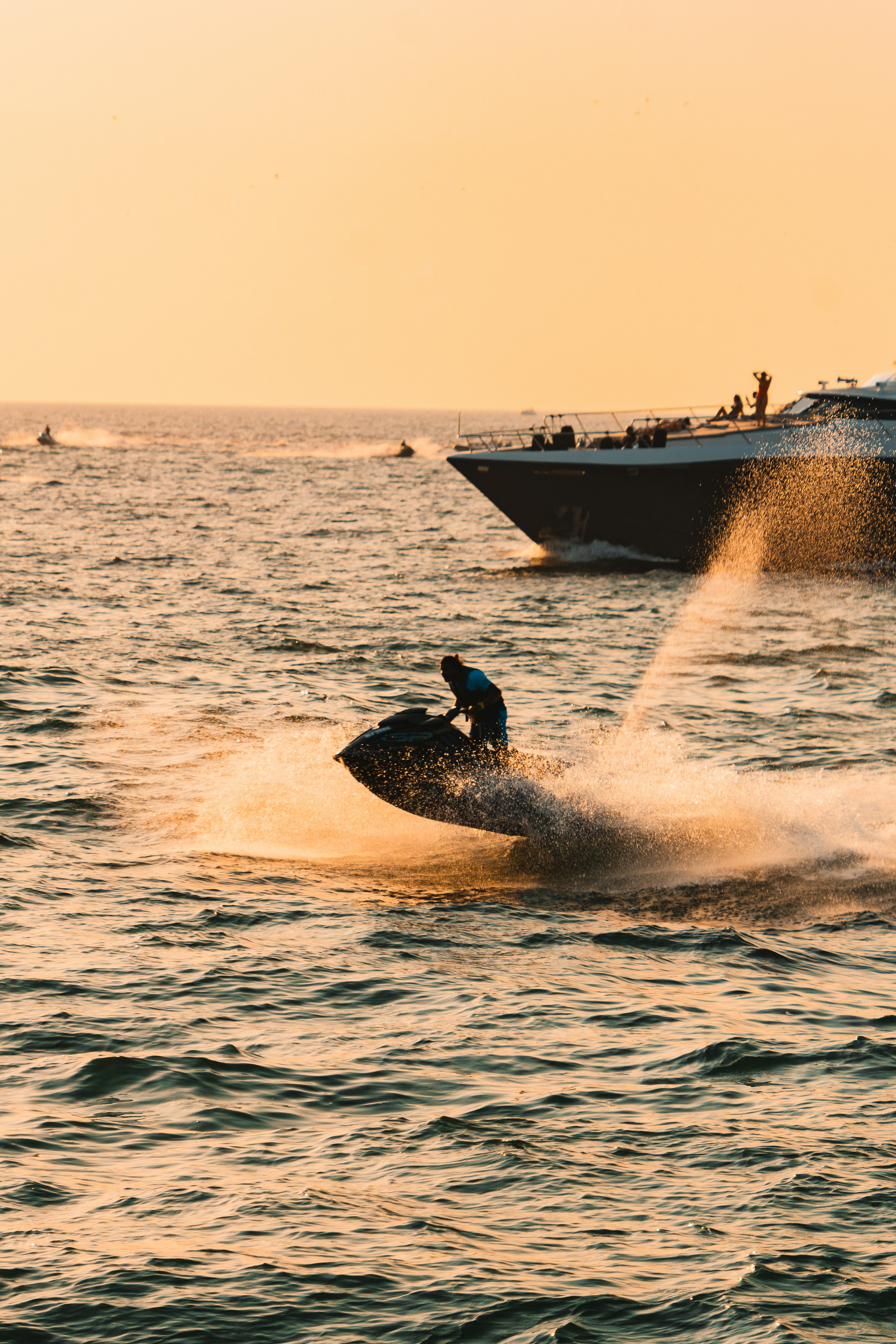 Personne faisant du jet ski avec un bateau en arrière-plan au coucher du soleil