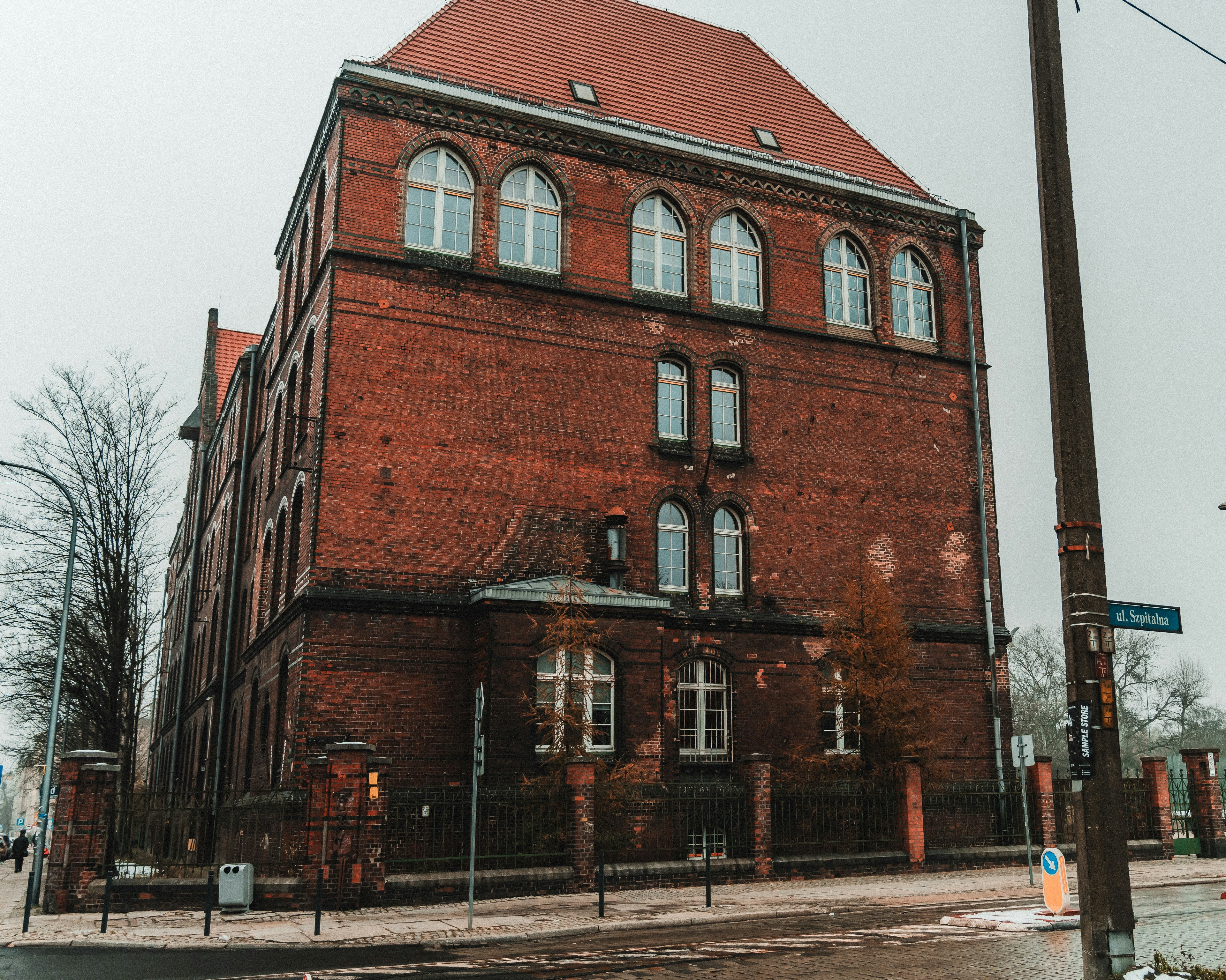 Ancien bâtiment en brique avec fenêtres cintrées et toit rouge.