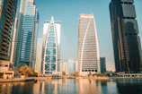 Modern skyscrapers reflect on the water in a city.