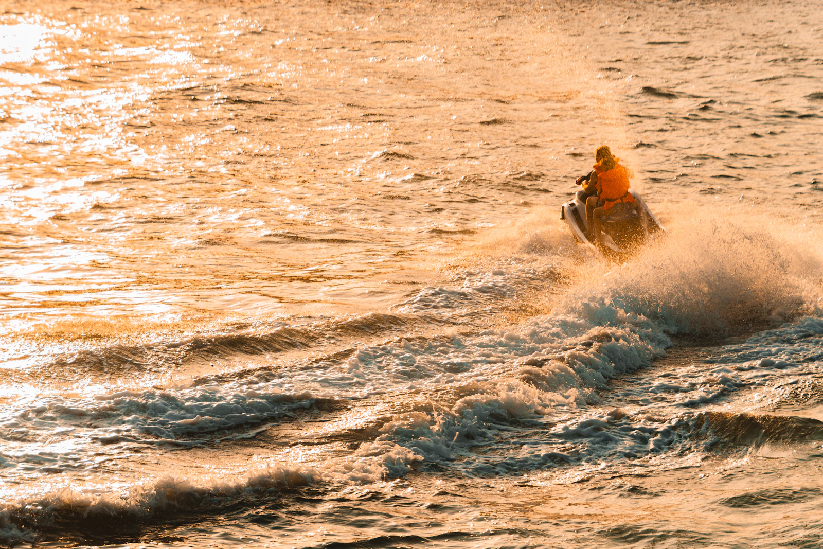 Jet ski rider throwing up spray off Dubai Marina at sunset