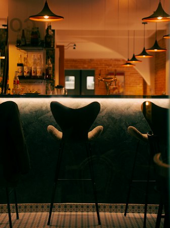 Empty chairs at a dimly lit neighborhood bar with pendant lights, similar to the quiet feeling of a longtime Las Vegas bar after its last night
