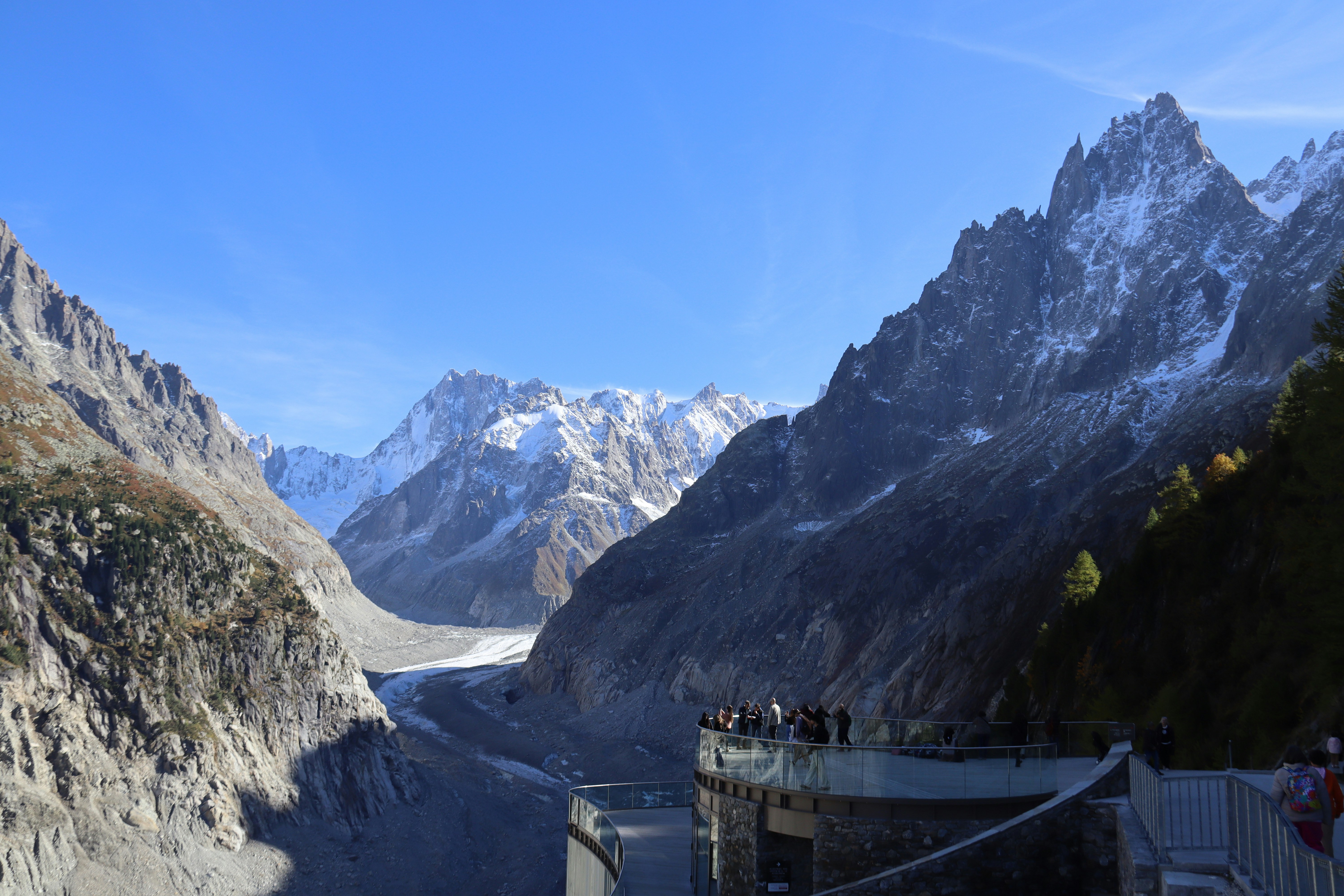 People observe a vast glacier between snowy mountains