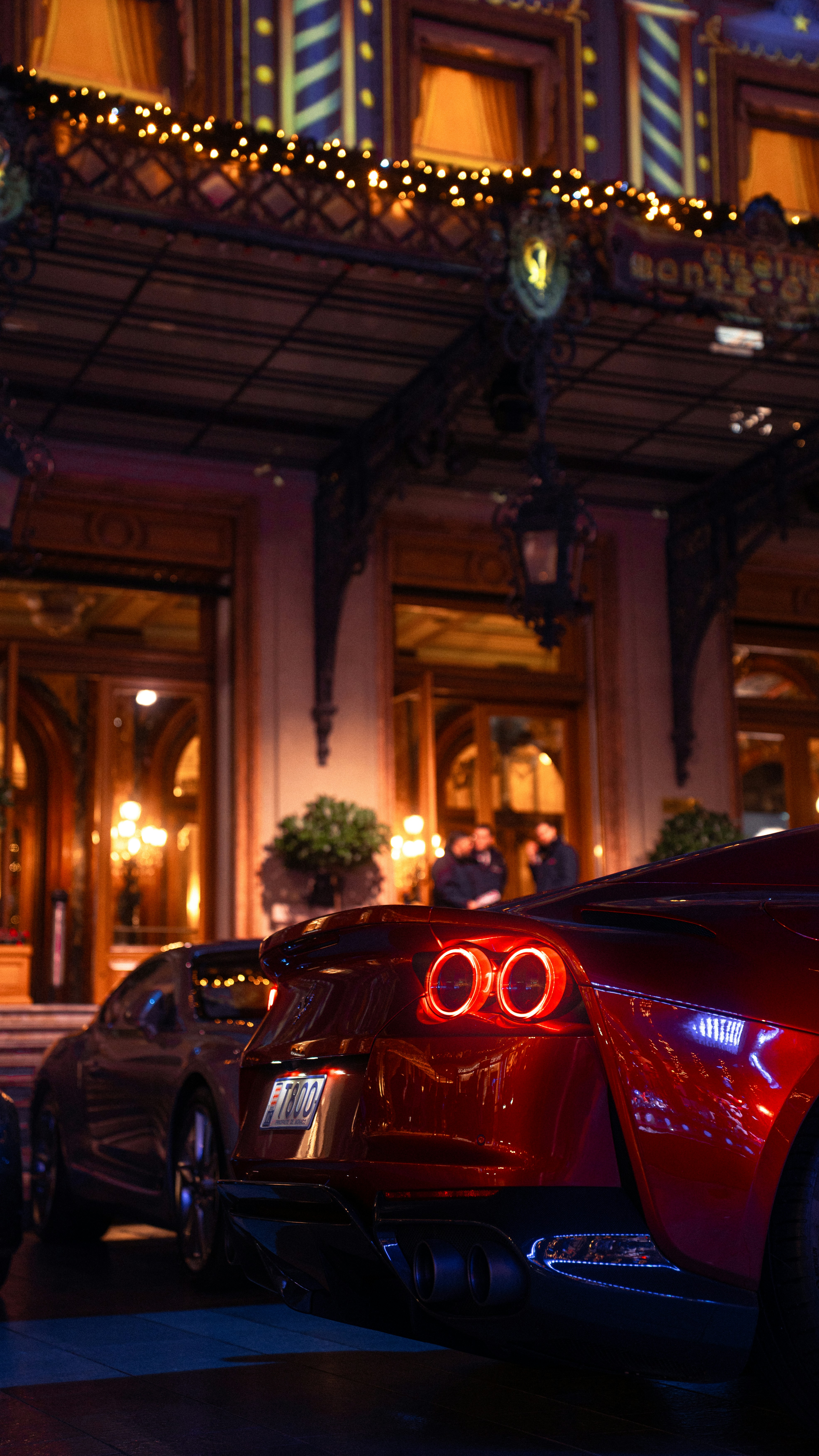Luxury cars parked outside a grand building at night.
