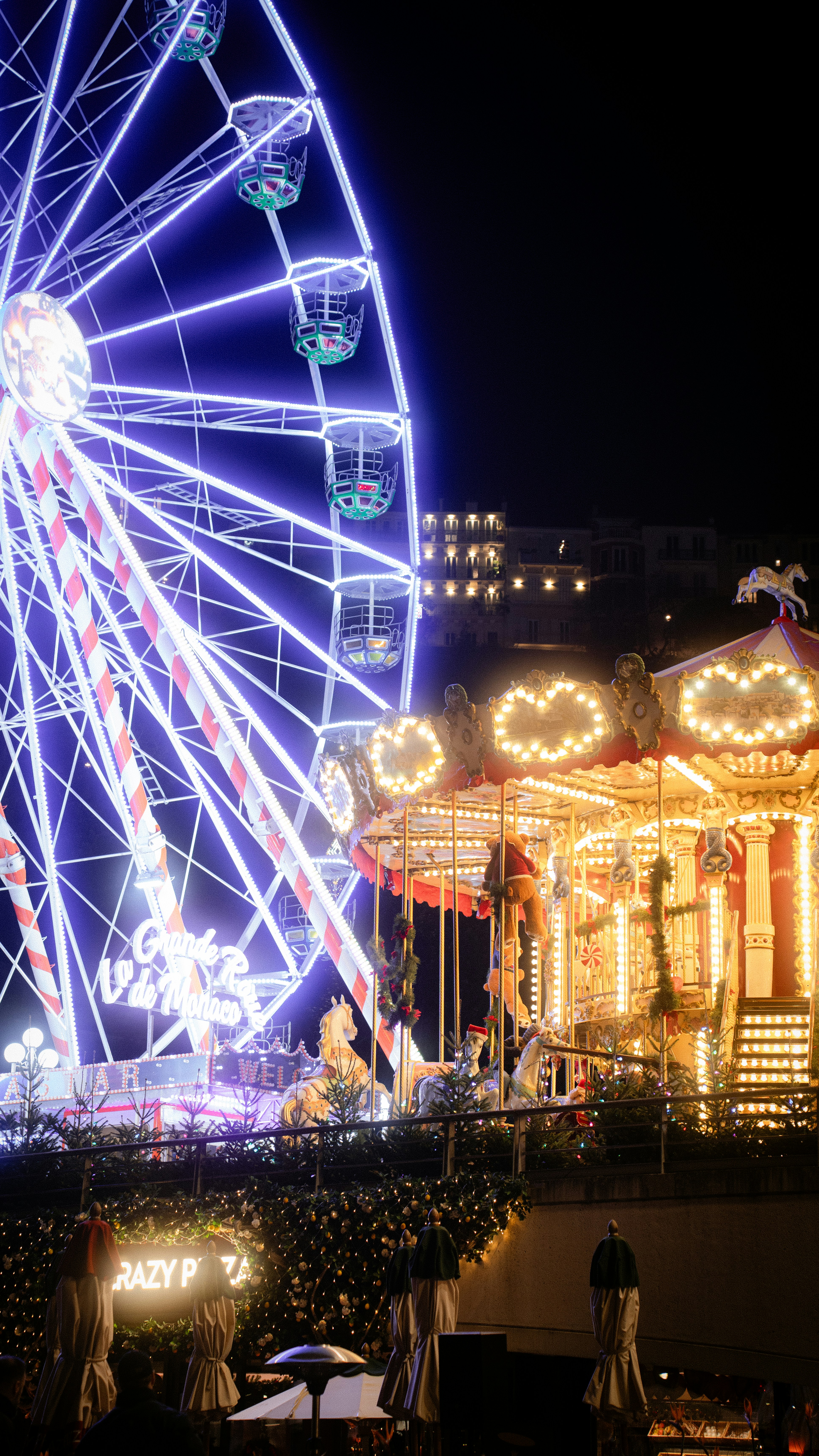 Ferris wheel and carousel at a nighttime amusement park