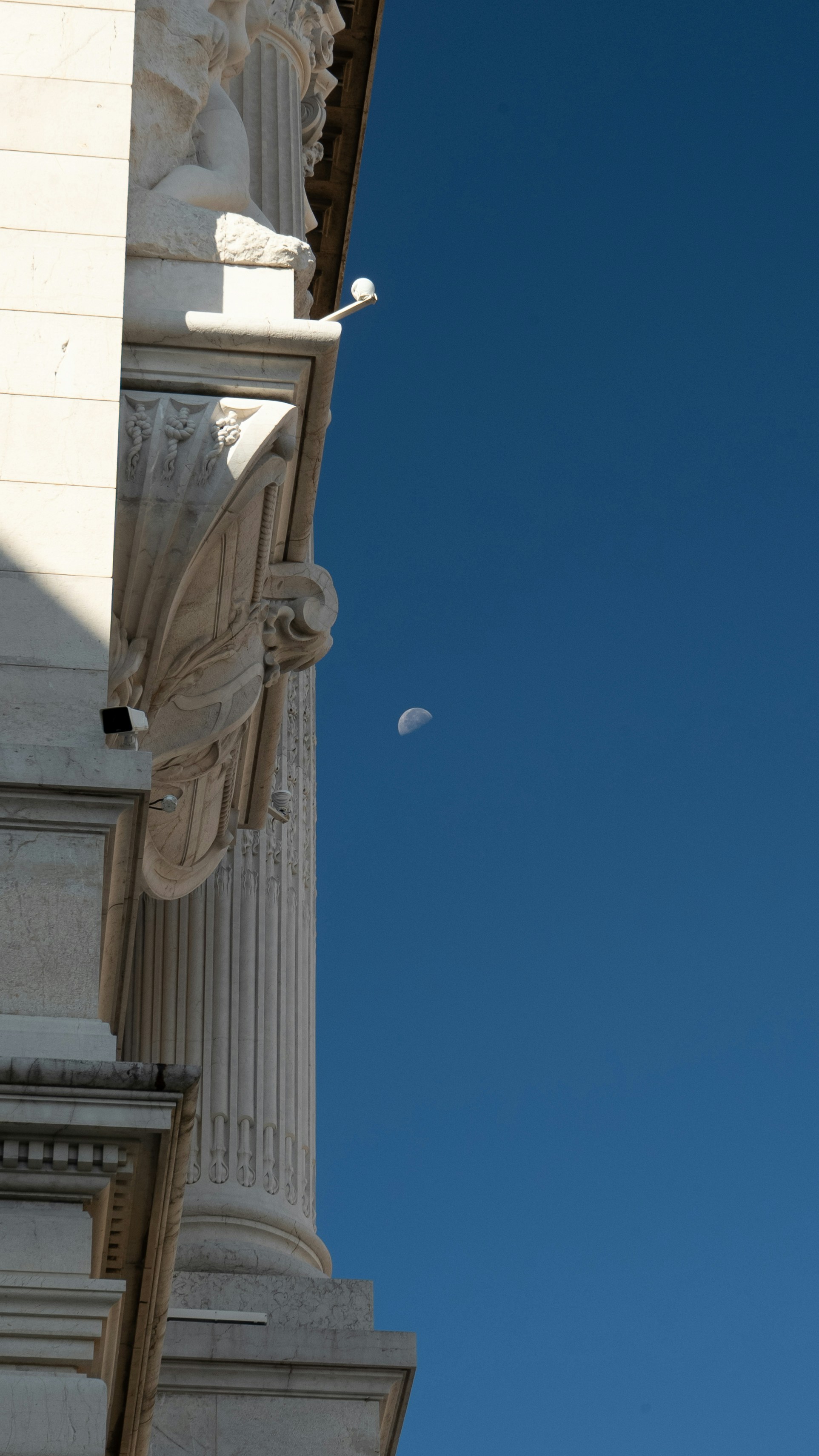 Building facade with moon in clear blue sky