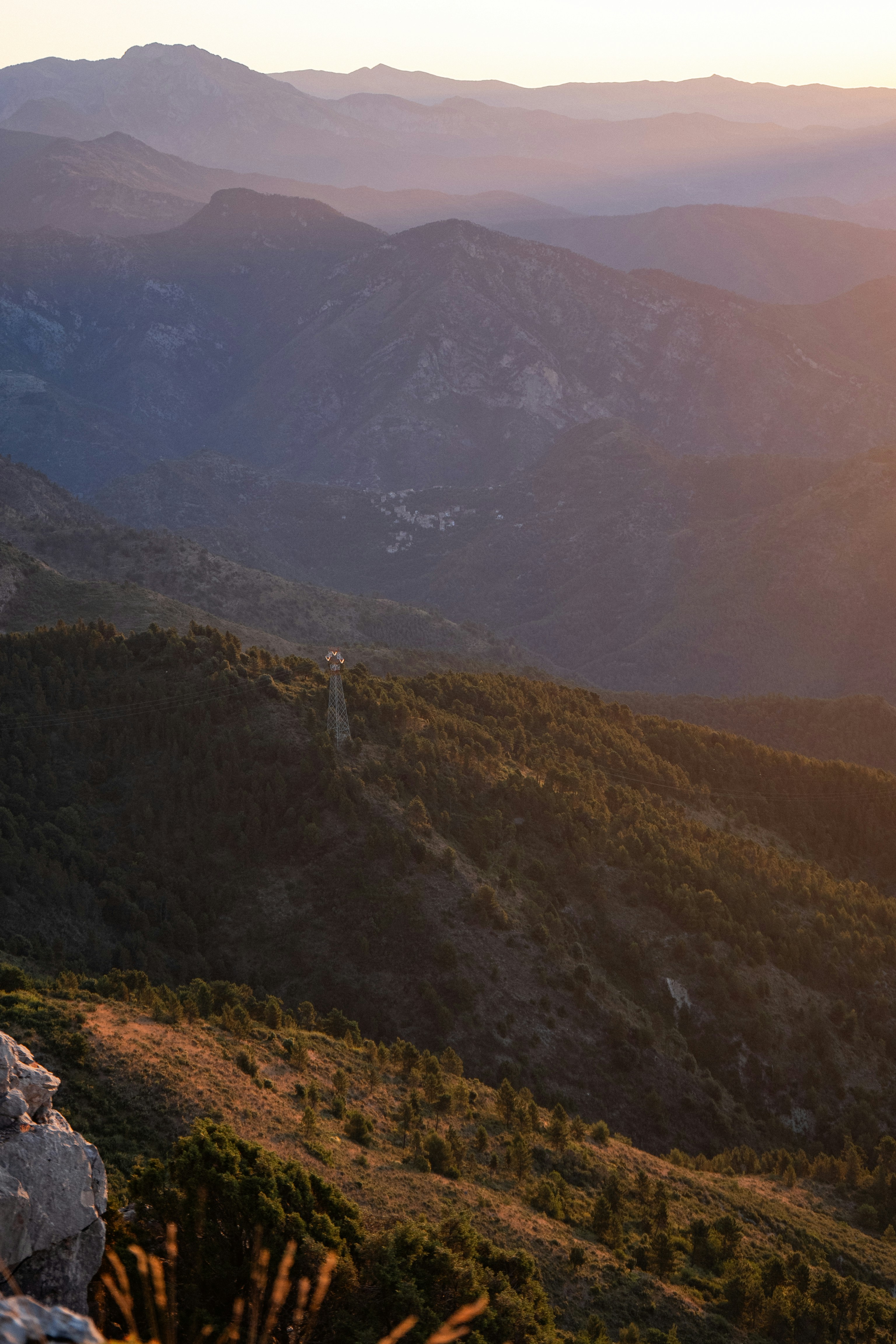 Rolling hills and mountains bathed in soft sunset light.