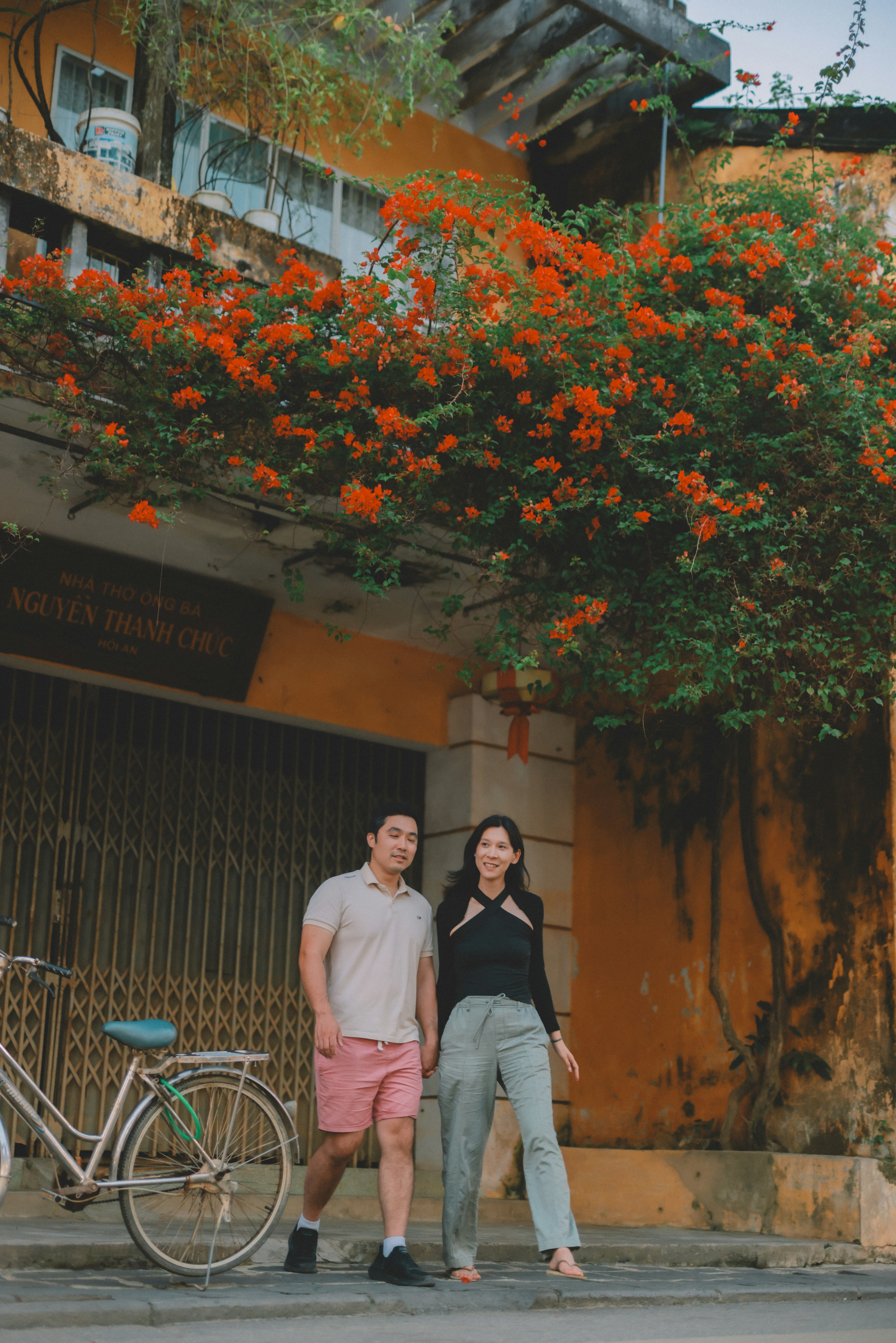 Couple walking past a building with orange flowers