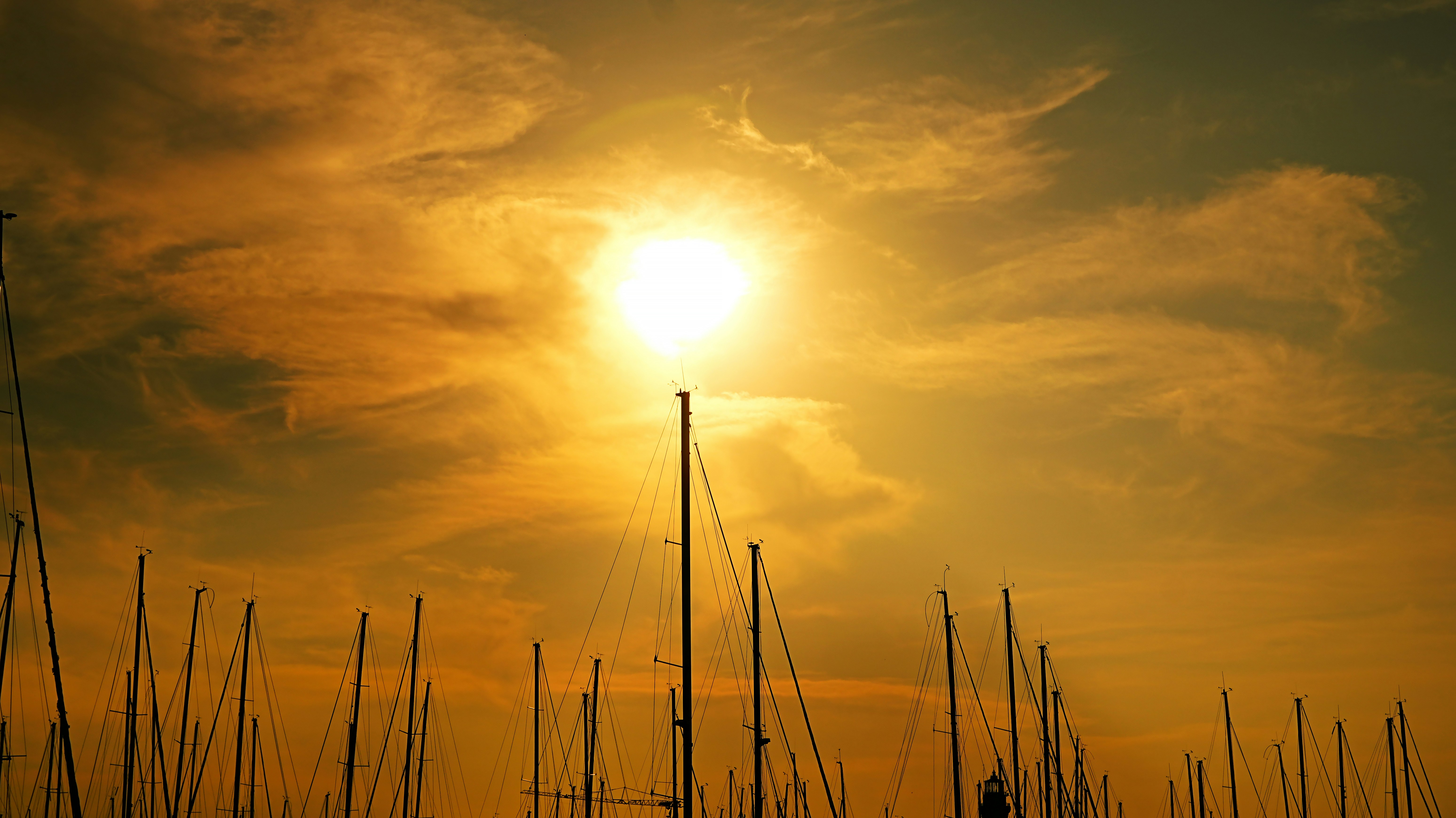Sun setting over a marina with sailboats.