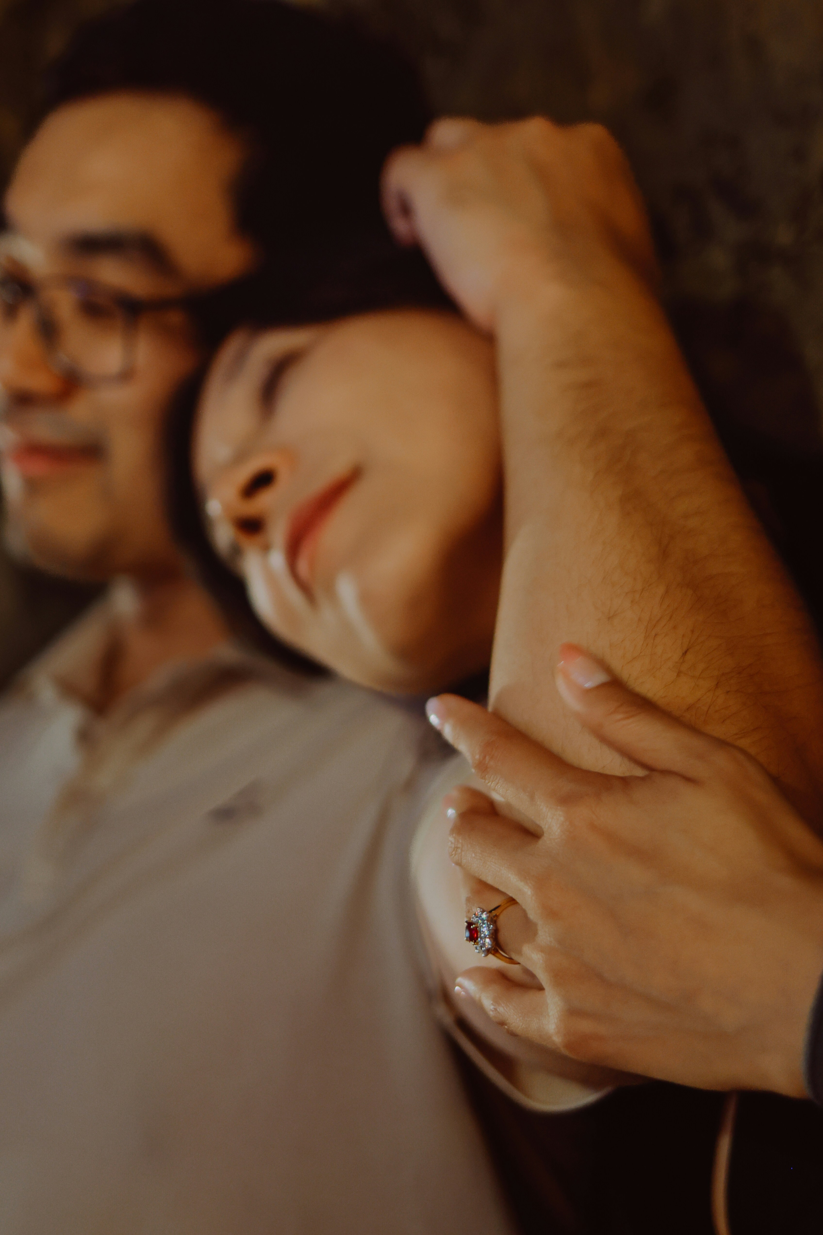 Couple embracing with woman resting head on man's arm.