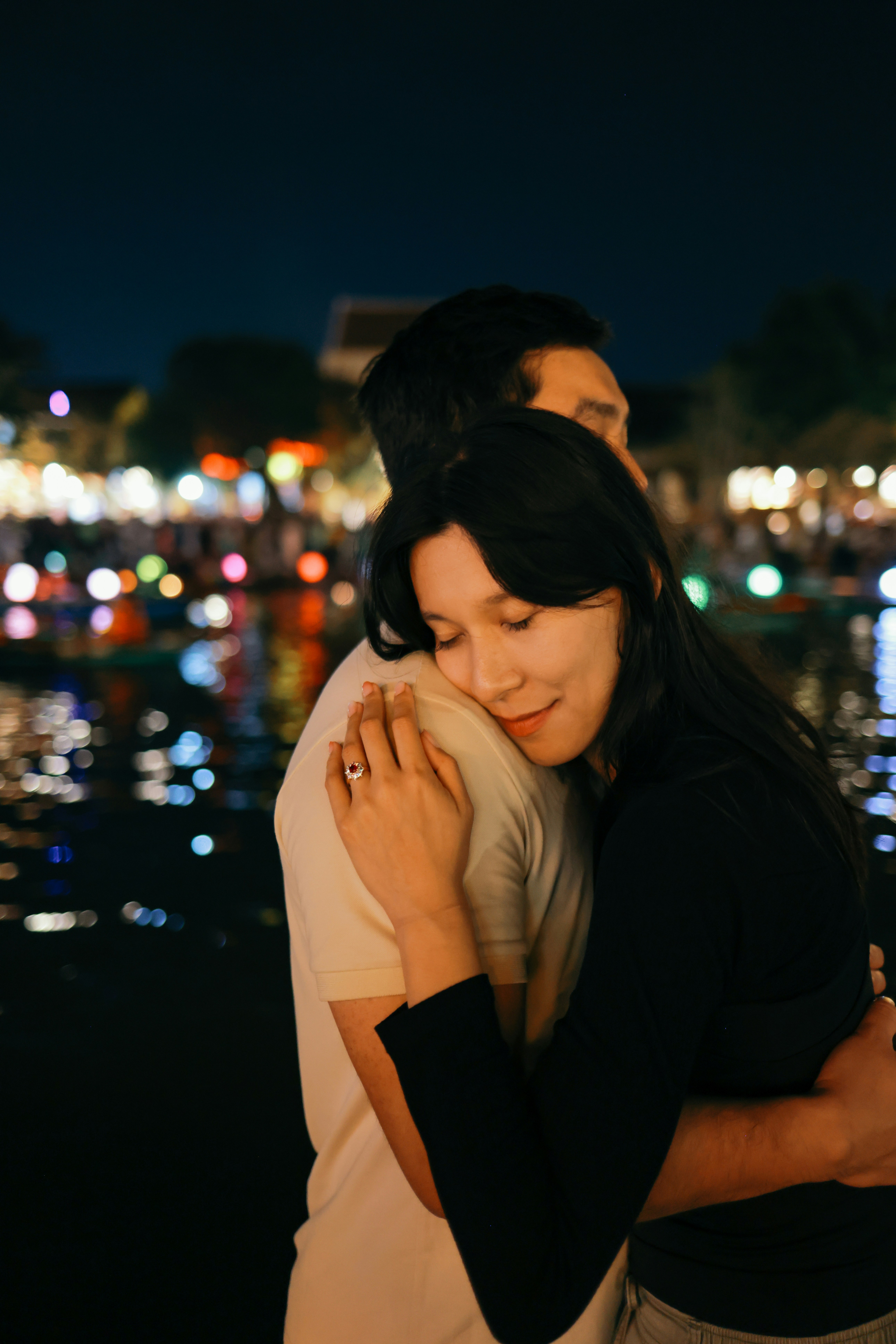 A couple embracing at night with bokeh lights