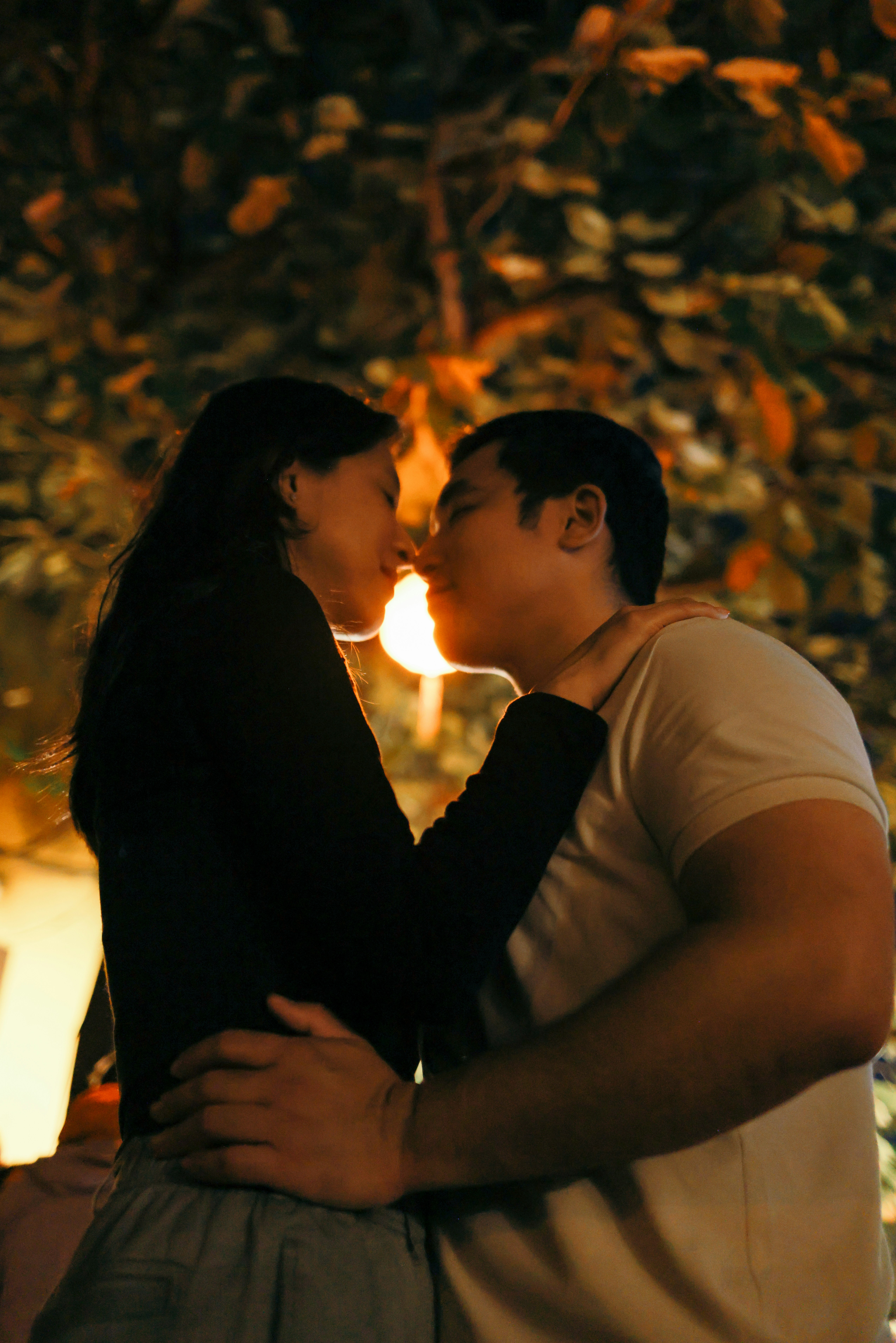 Una coppia che si abbraccia e sta per baciarsi all'aperto.