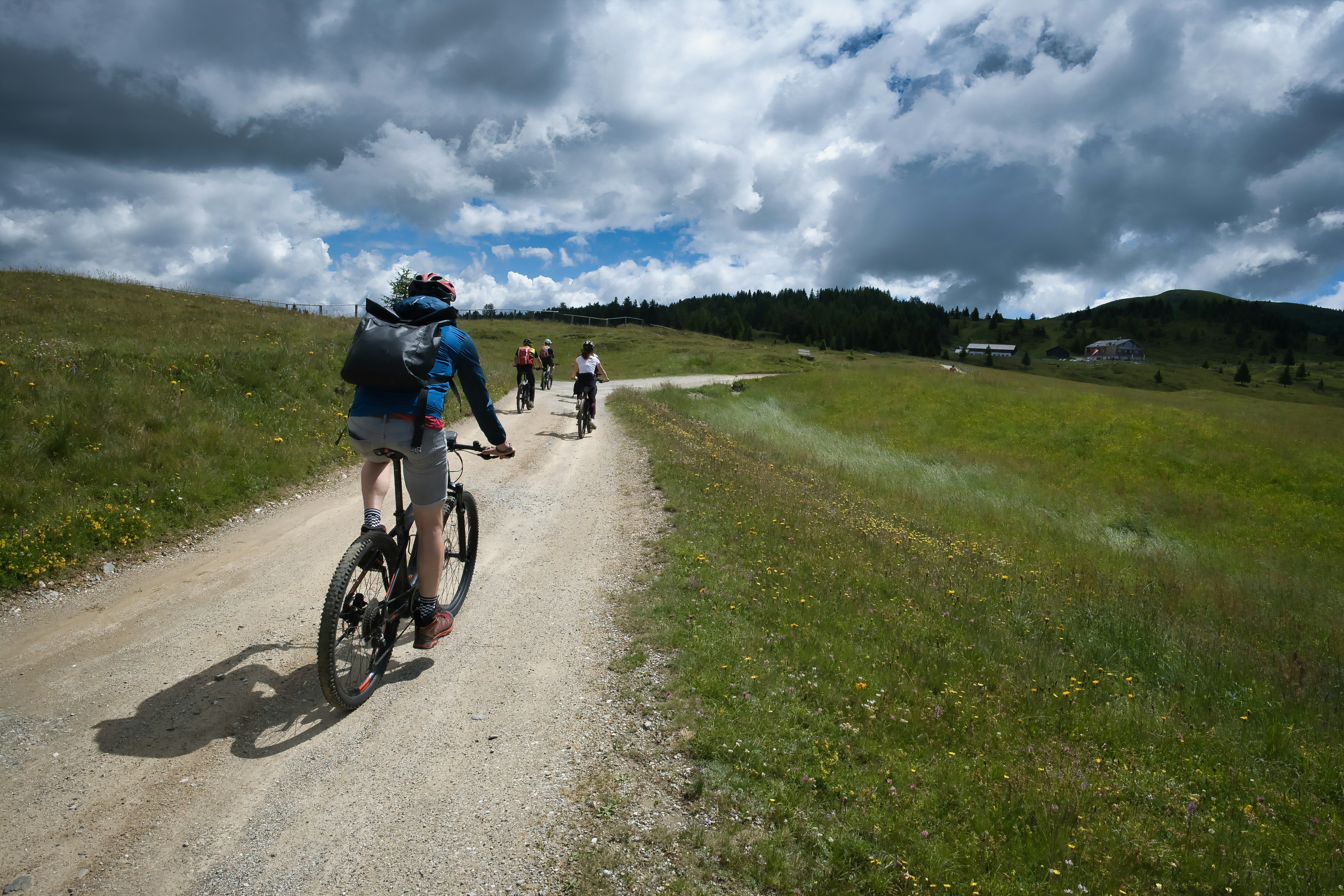 Cyclists riding on a dirt path through grassy hills.