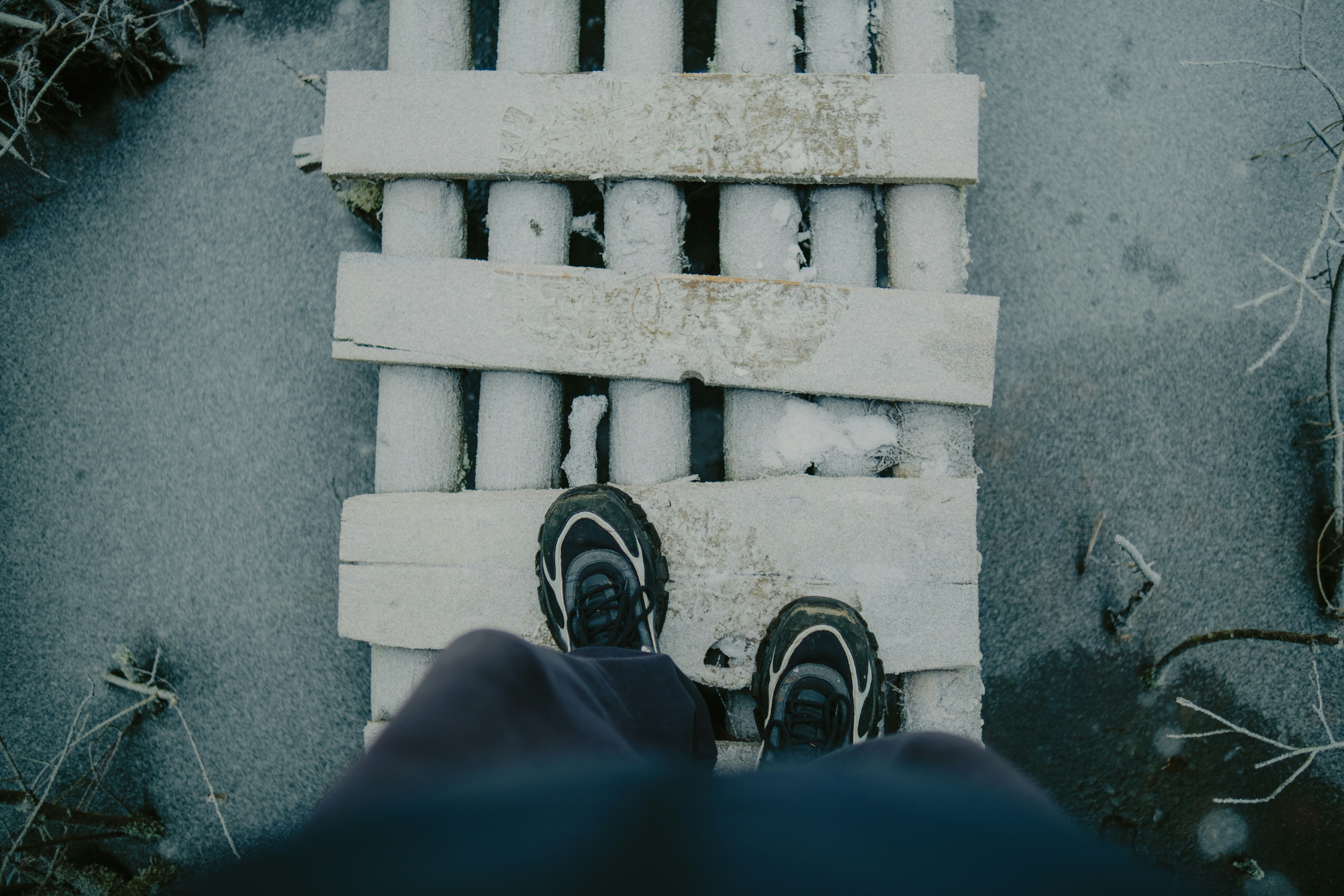 Person standing on a wooden bridge over frozen water.