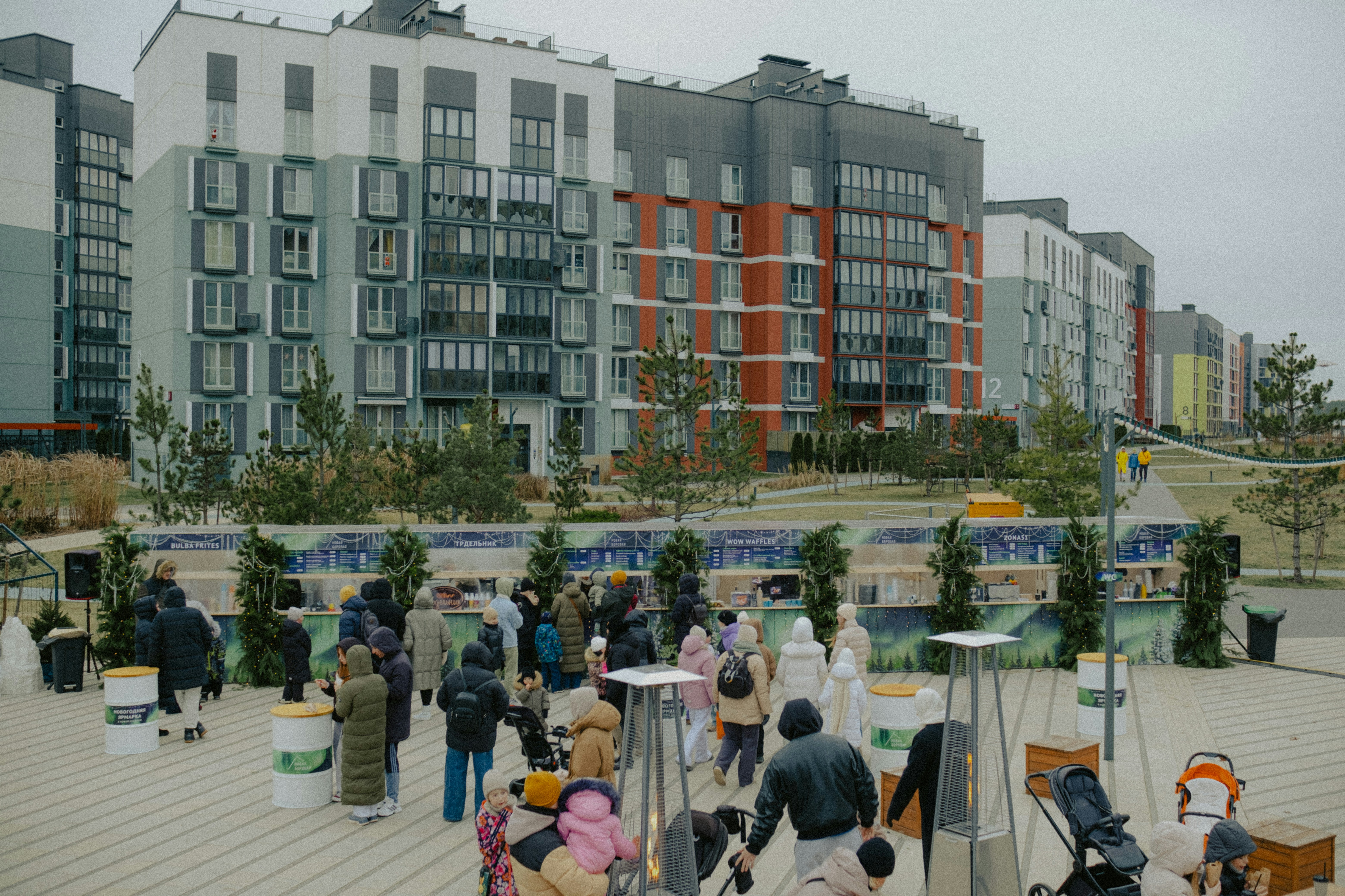 People gathered outside modern apartment buildings on a cloudy day