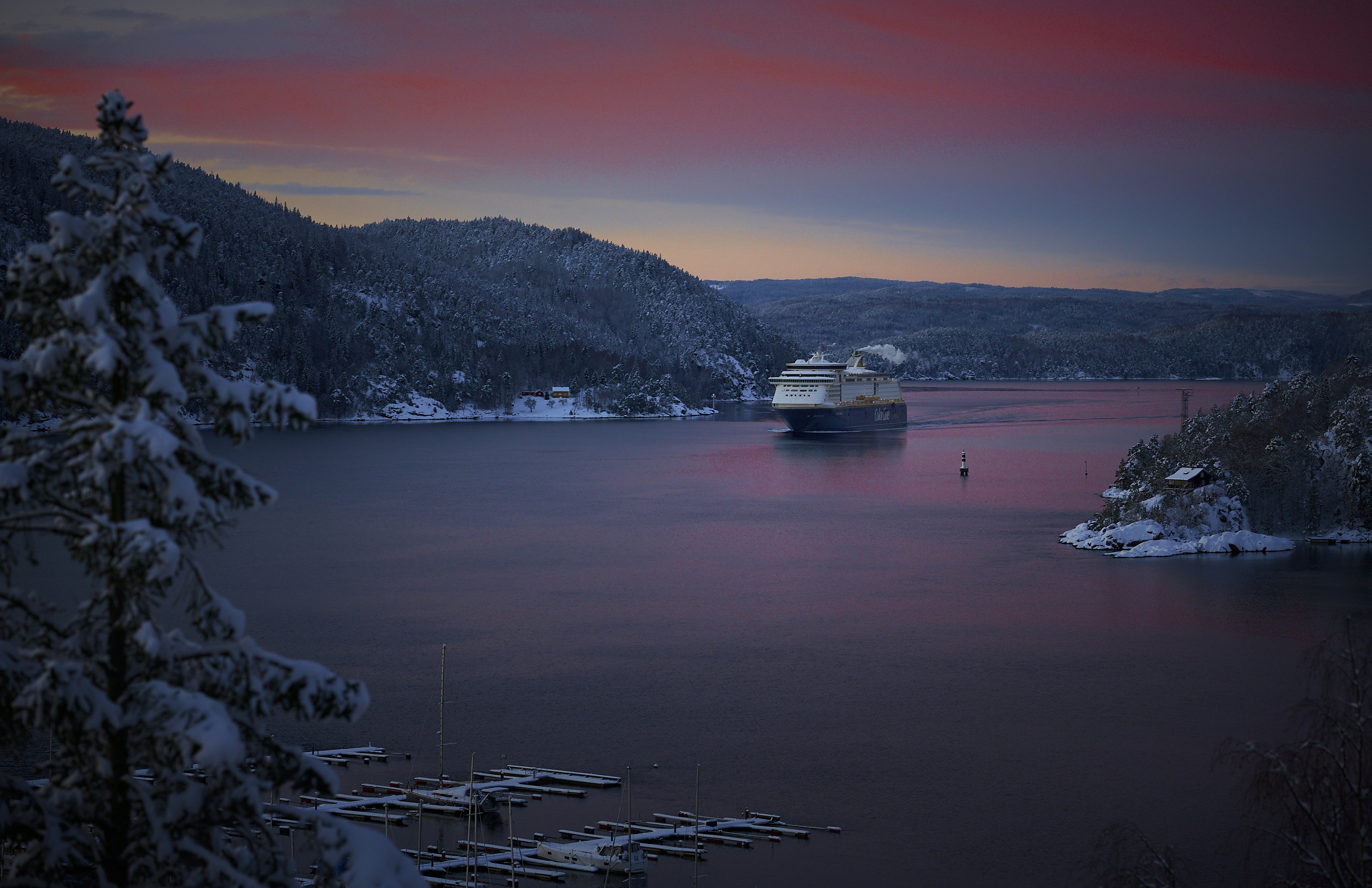 Paisaje nevado con lago y un cielo colorido al atardecer.