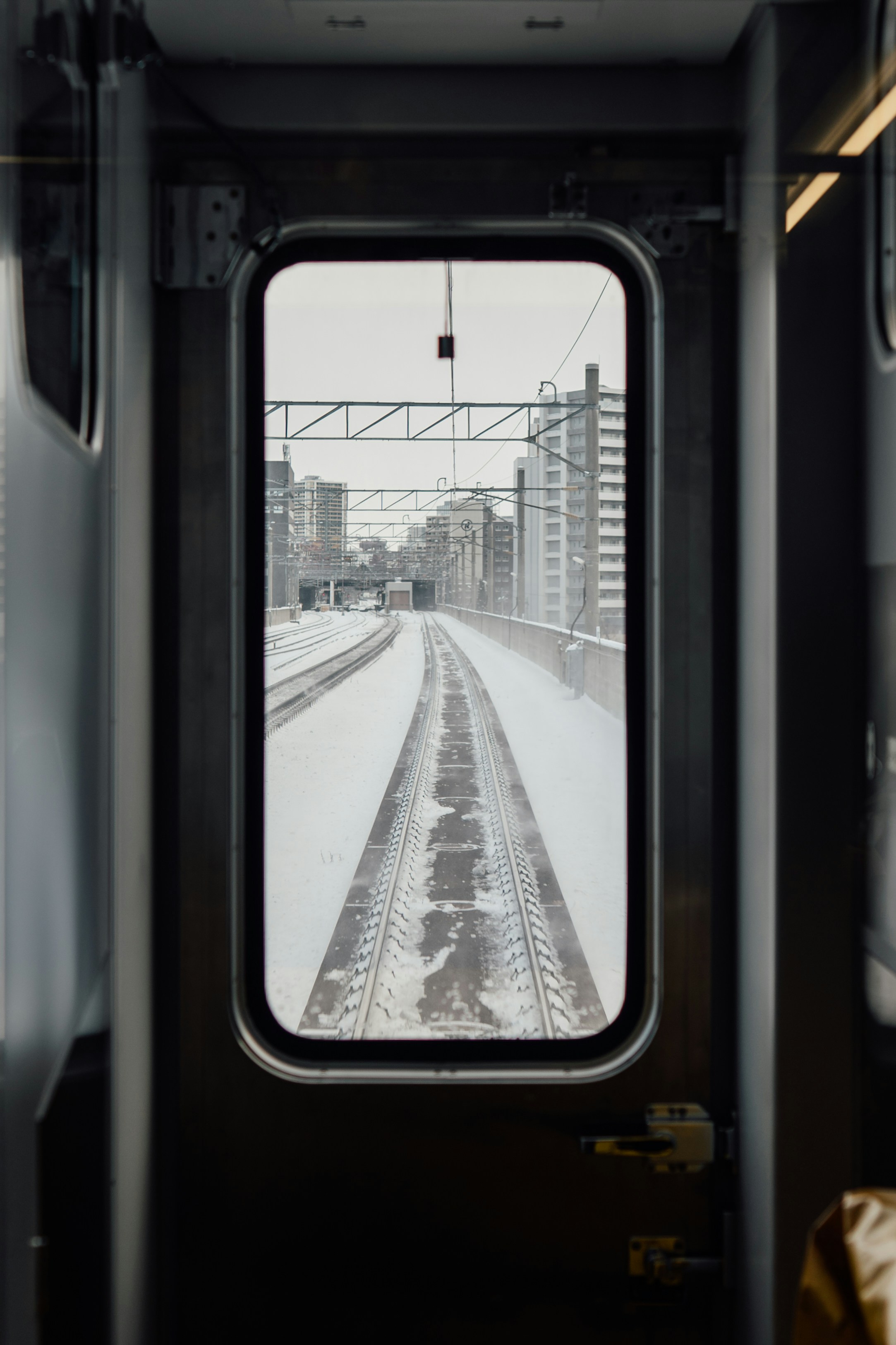 View of snowy train tracks through a window.