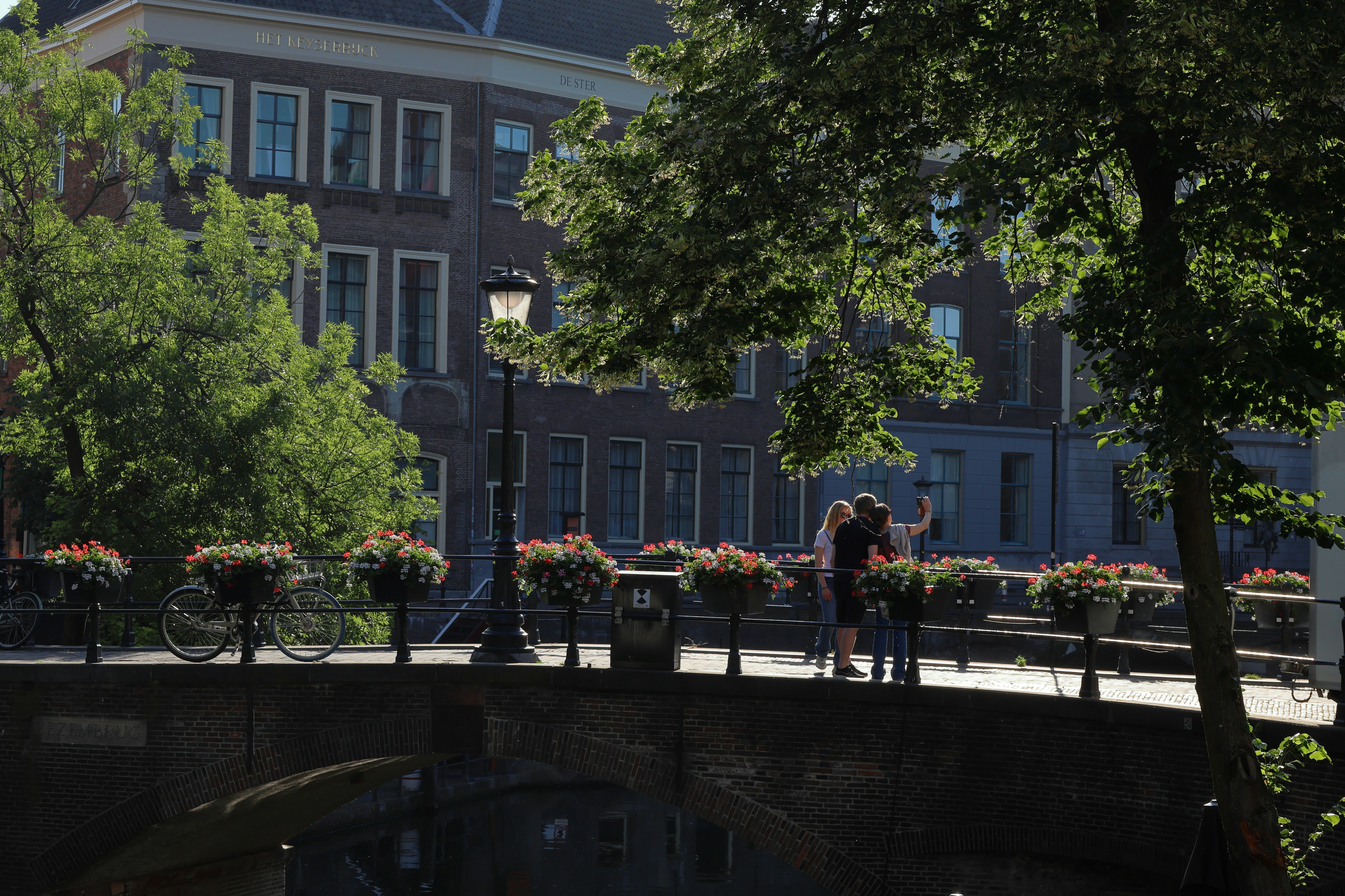 Casal tirando uma selfie em uma ponte com flores.
