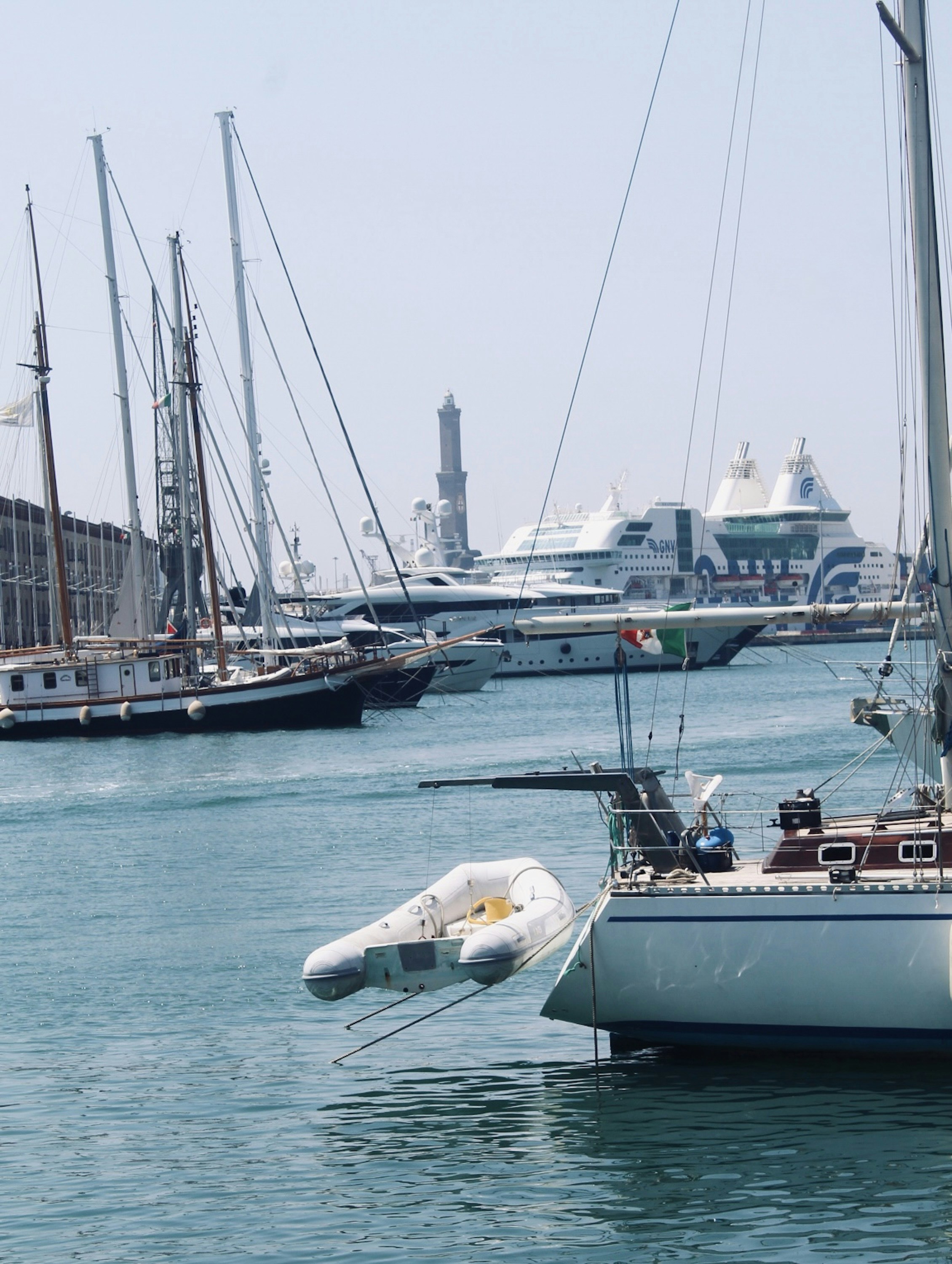 Sailboats and yachts docked in a sunny harbor.