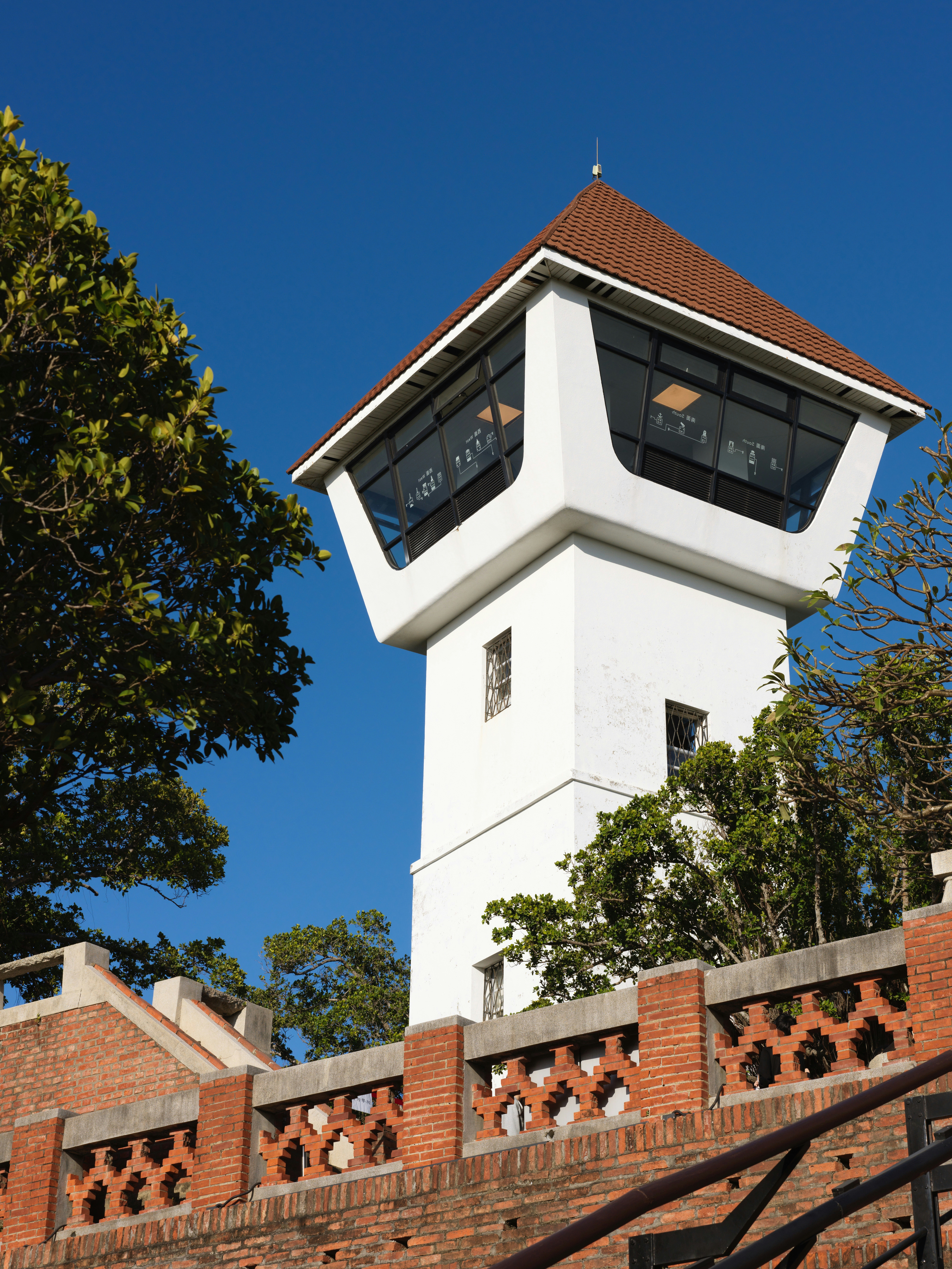 White tower with a glass observation deck and brown roof.