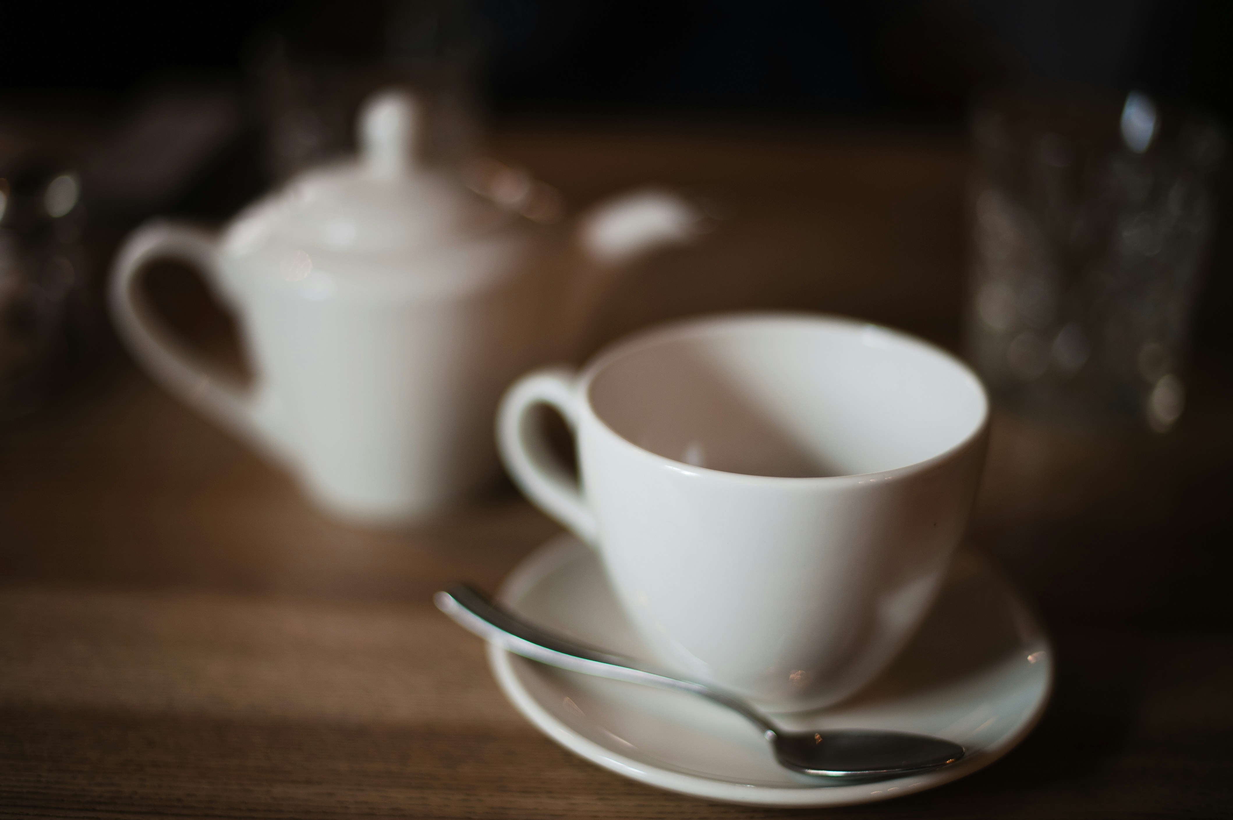 White teacup and saucer with spoon and teapot